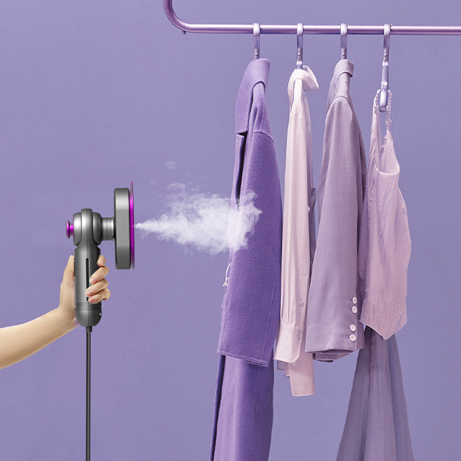 Eine Hand hält einen Steamer und dämpft Kleidung, die auf einem Gestell hängt.