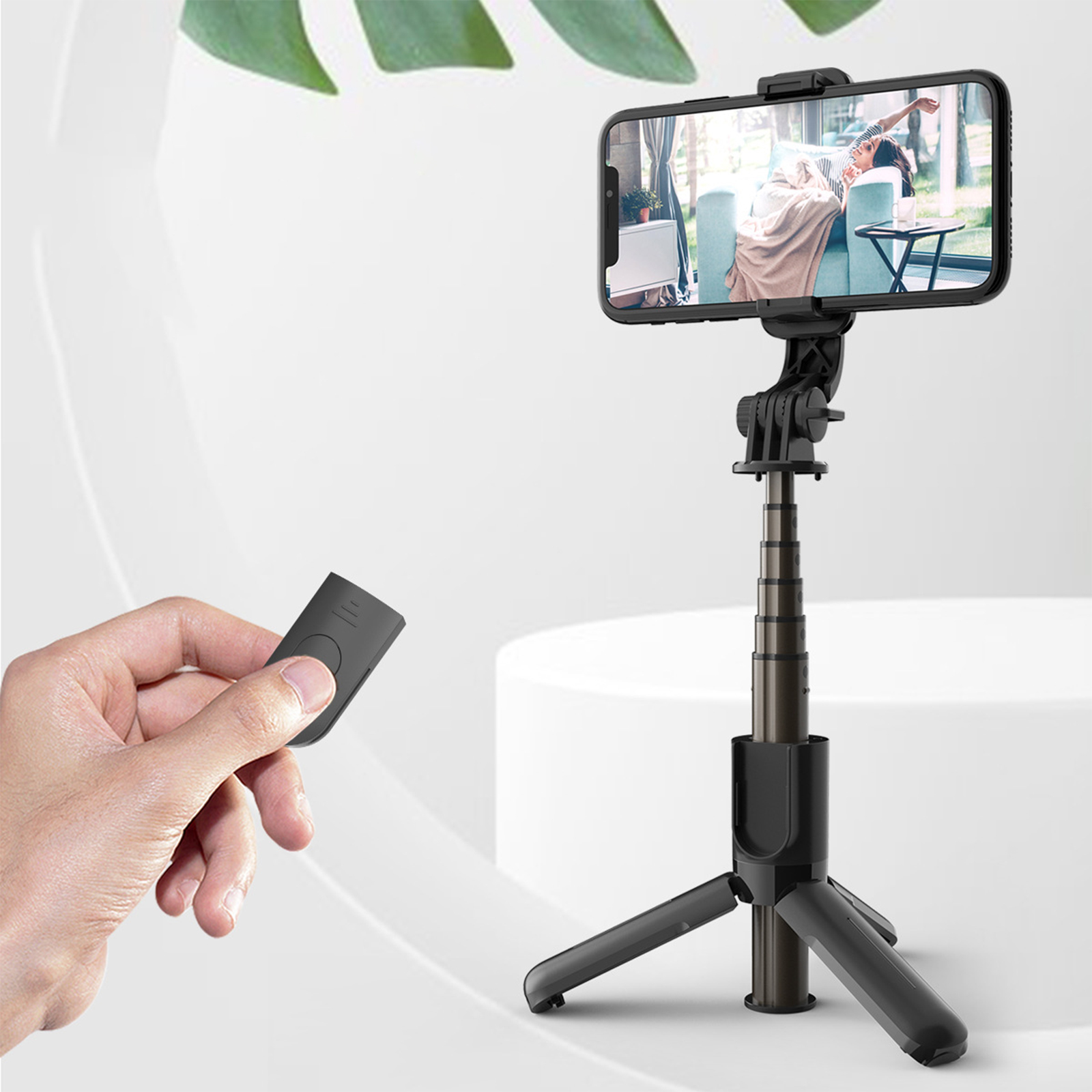 Person benutzt ein Telefon auf einem Stativ. Eine andere Person hält eine Fernbedienung. Weißer Hintergrund.