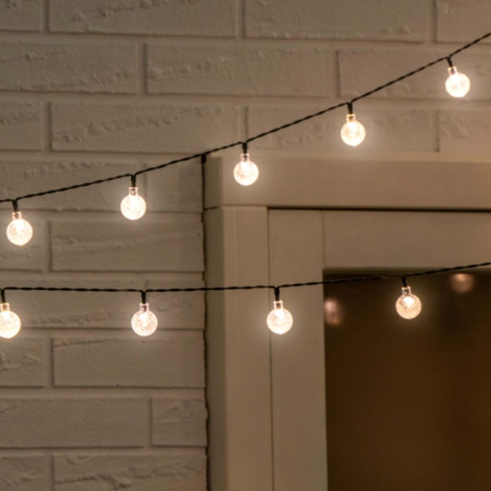 Slingers met ronde lampen tegen een bakstenen muur. Warm licht.