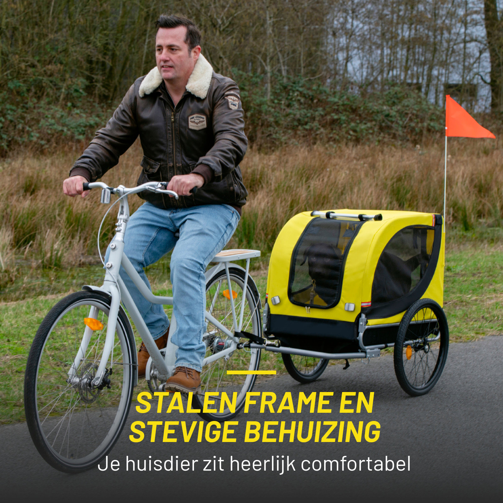 A man rides a bike with a yellow pet trailer. A red flag is on the trailer. The road is black.