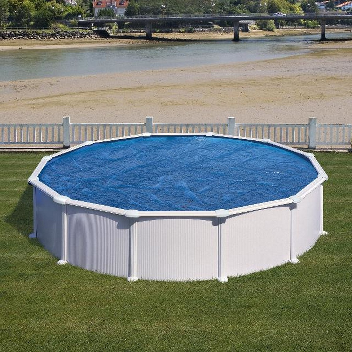 Ein oberirdischer Pool mit einer blauen Abdeckung, weißem Zaun und grünem Gras drumherum.
