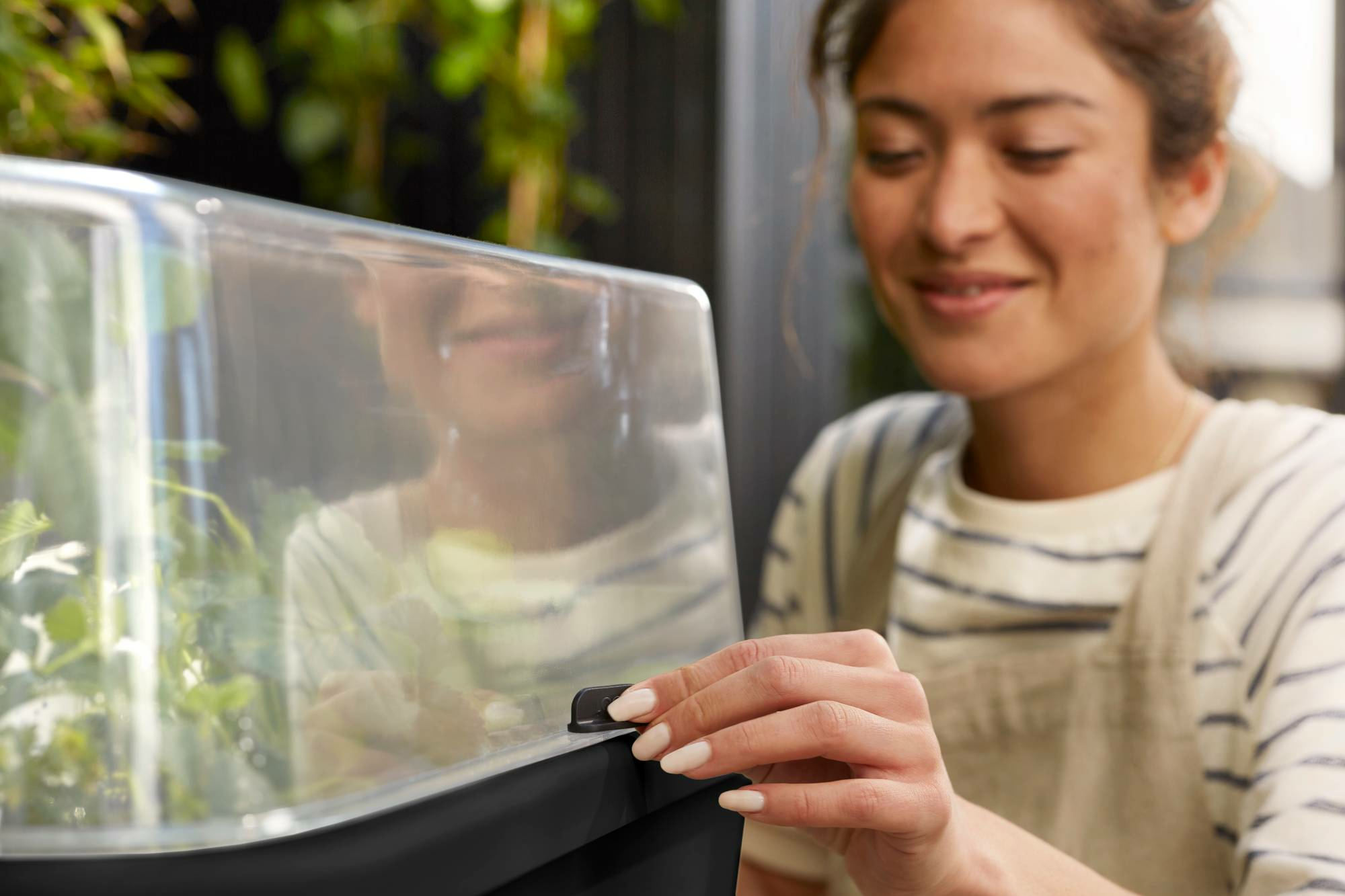 Kobieta zamyka pokrywę grządki. Marka Elho widoczna.