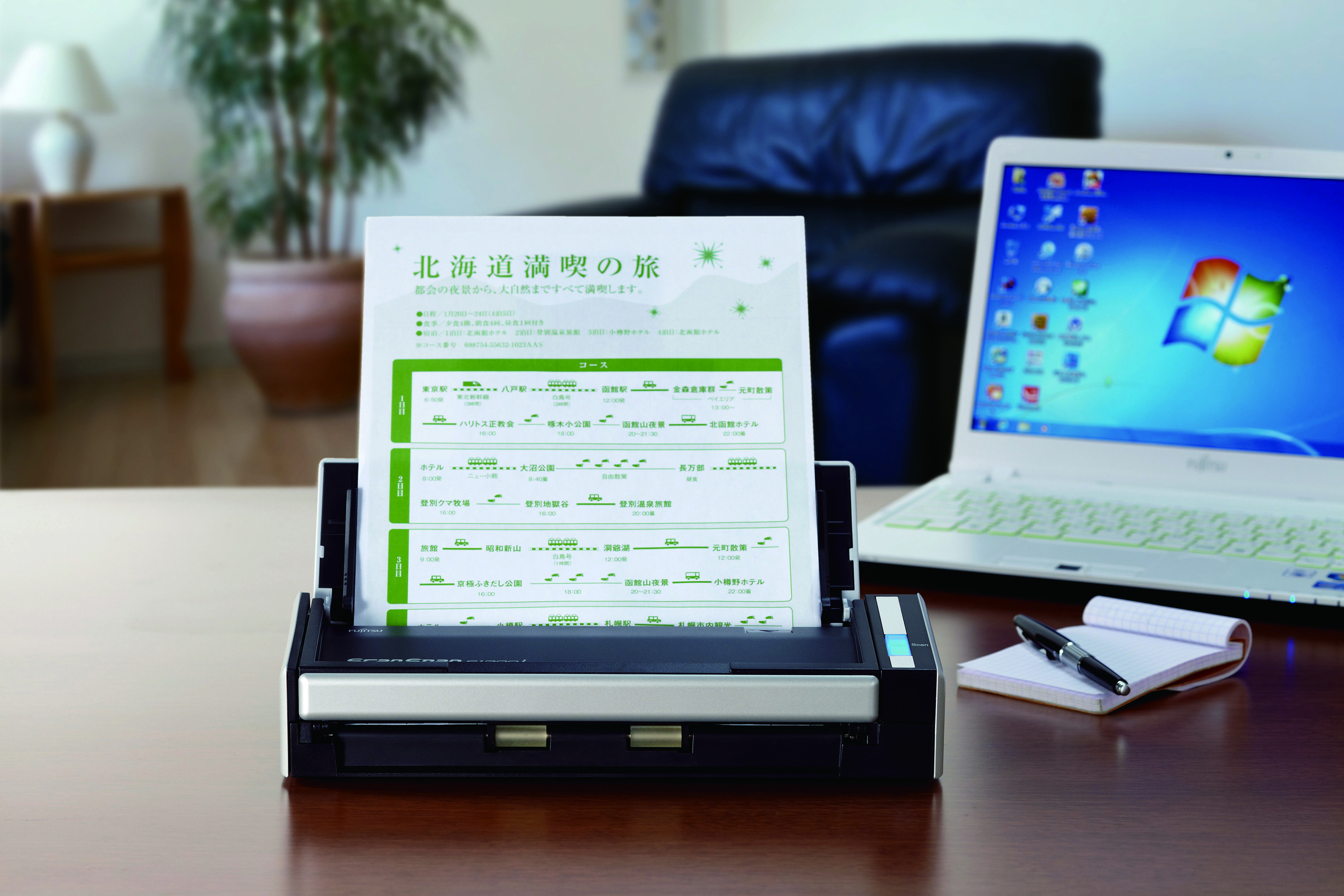 Skaner na biurku z laptopem i długopisem. Skanowany jest papier z japońskim tekstem.