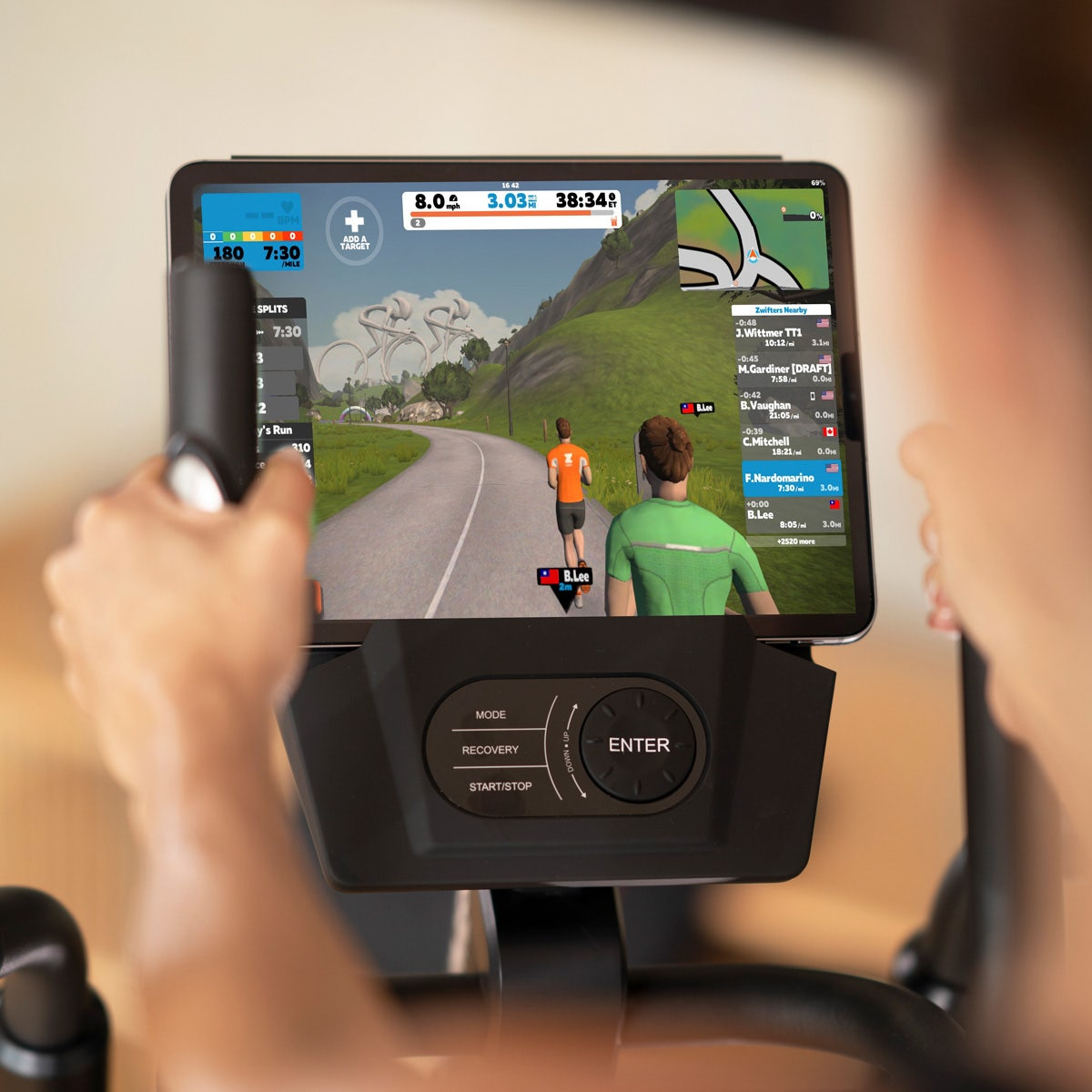 Person nutzt Tablet zum Radfahren auf einem Heimtrainer mit virtuellem Training.