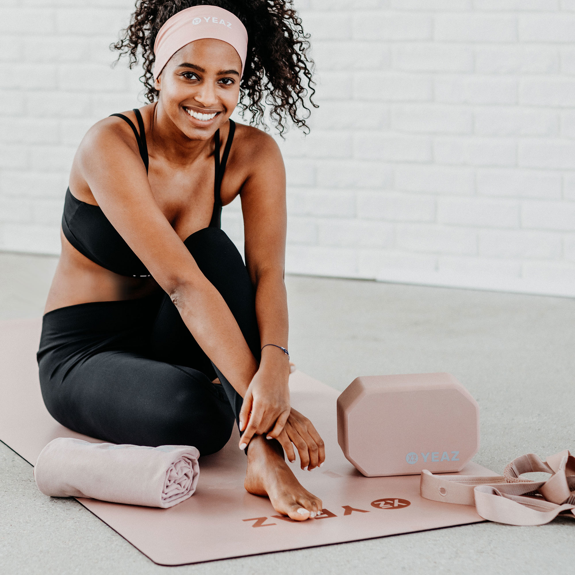 Frau sitzt auf Yogamatte mit Yoga-Zubehör.