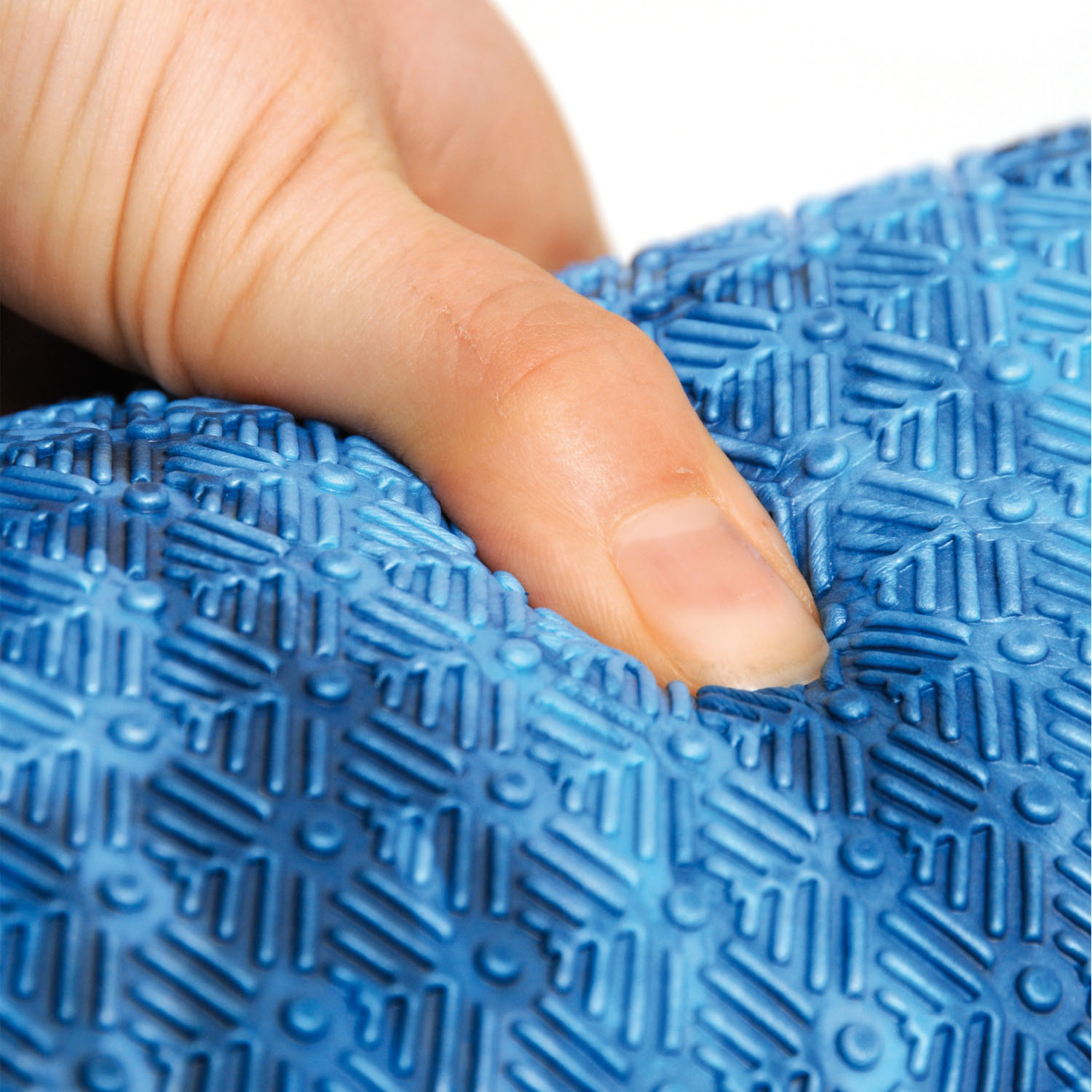 Dłoń naciska na niebieską, teksturowaną powierzchnię.
