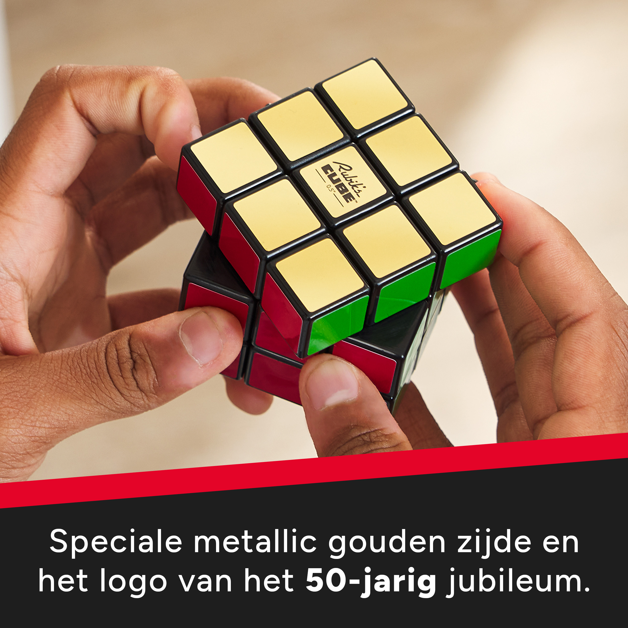 Mani che tengono un cubo di Rubik dorato. Lati rossi e verdi visibili. Logo dell'edizione speciale.