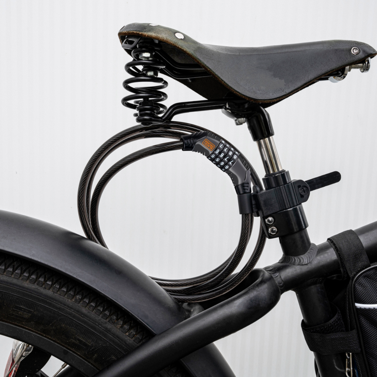 Een fietszadel met een combinatieslotkabel eromheen gewikkeld. De fiets is zwart.
