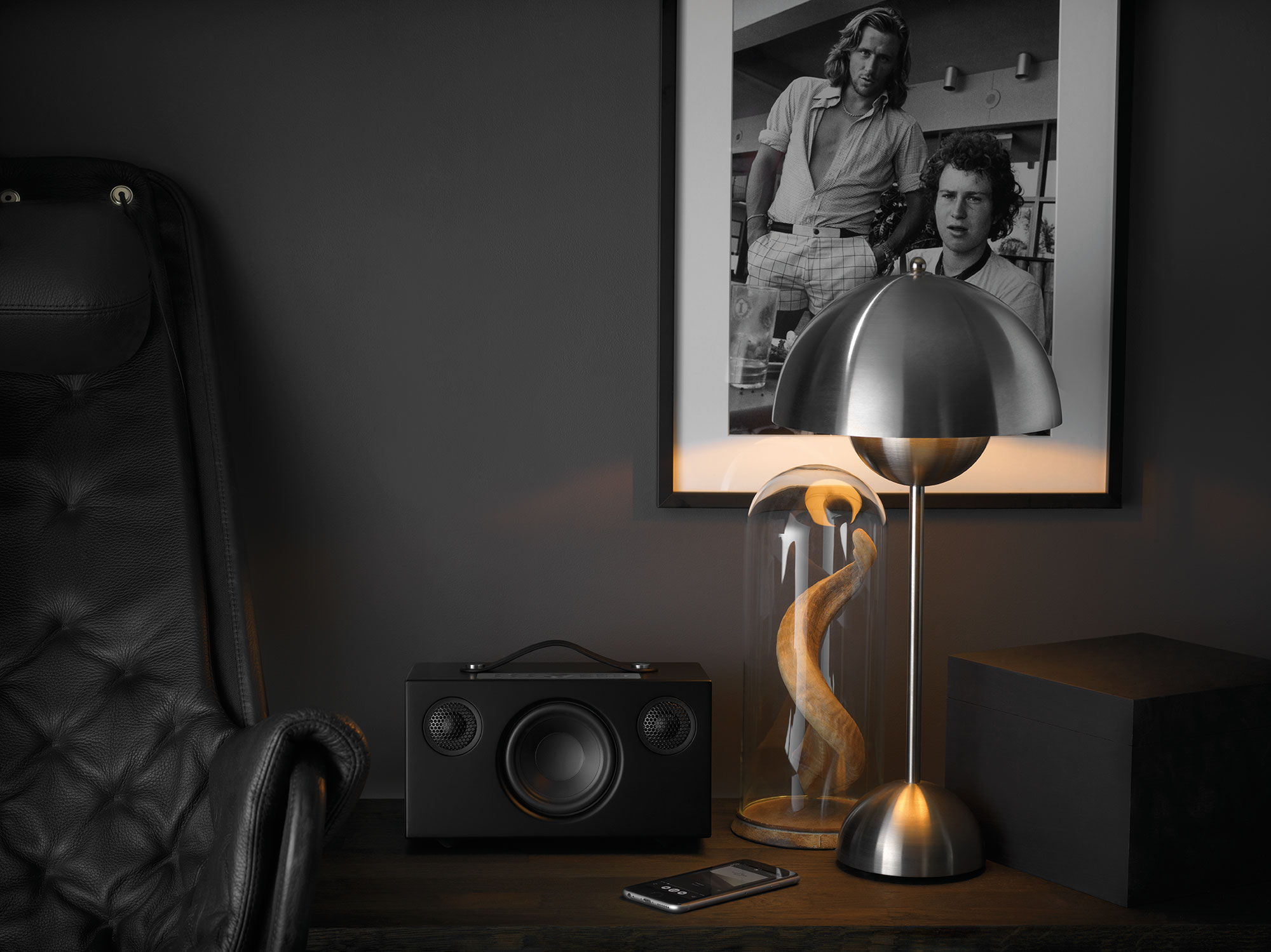 Stanza moderna con lampada, altoparlante e arte. Una foto in bianco e nero è appesa al muro.