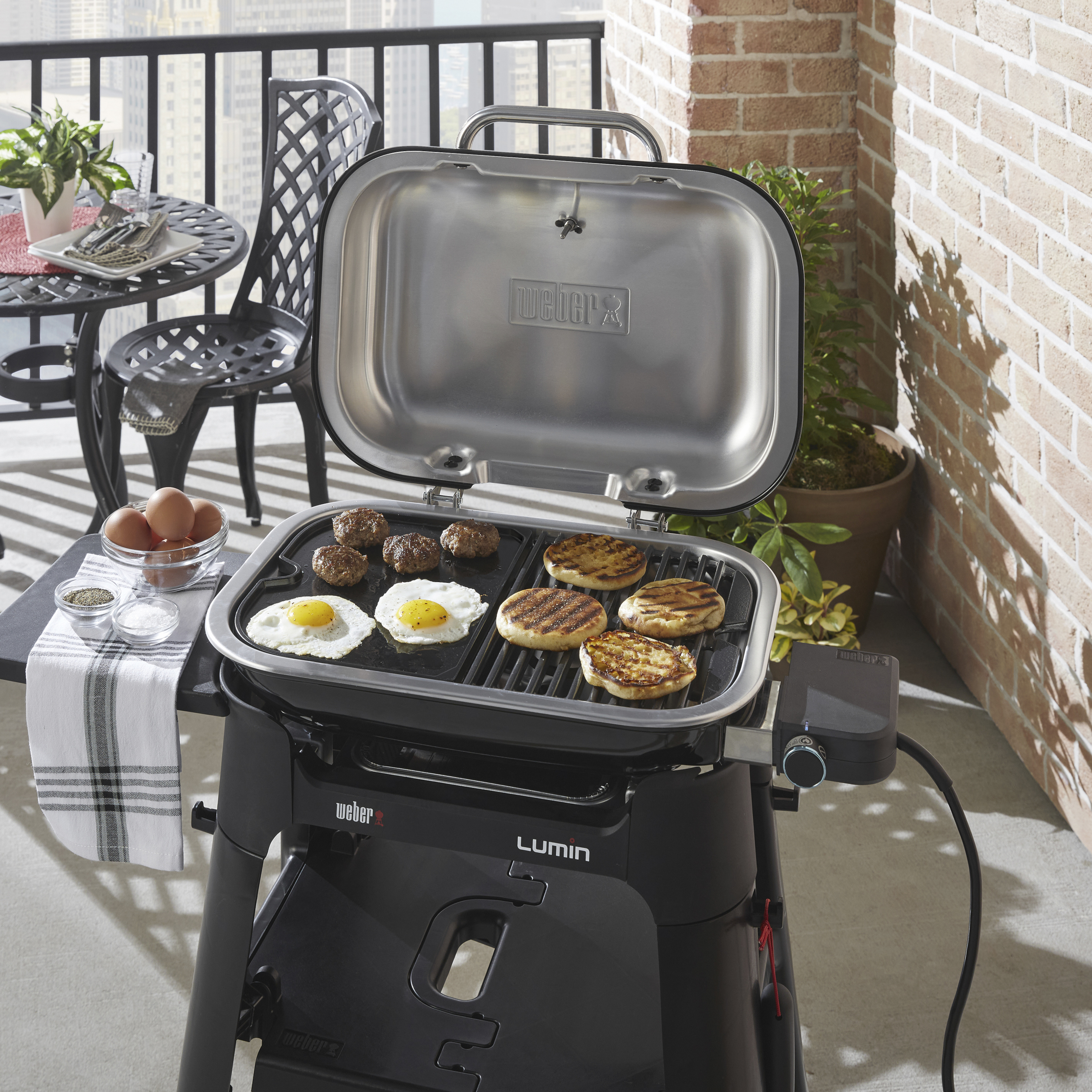 Grill Weber Lumin na patio, z ugotowanym jedzeniem na grillu, stół z jajkami.
