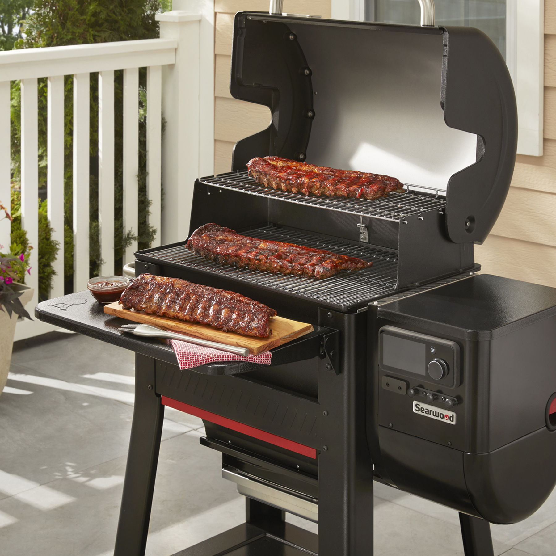 Una parrilla con costillas en la parrilla y una tabla de cortar con costillas a un lado.