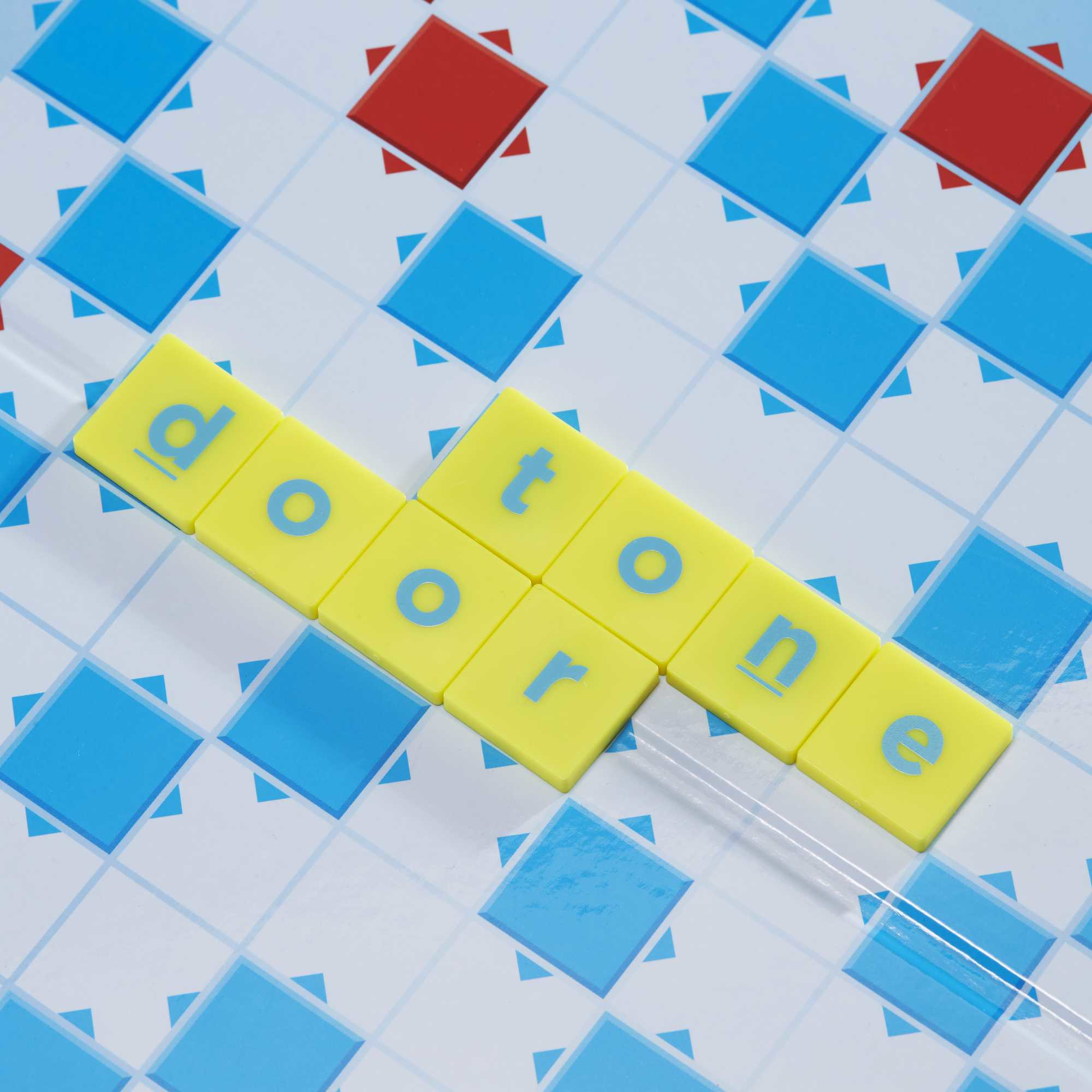 Ein Brettspiel, das das Wort „door tone“ auf farbigen Kacheln zeigt. Blaue und rote Kacheln umgeben.