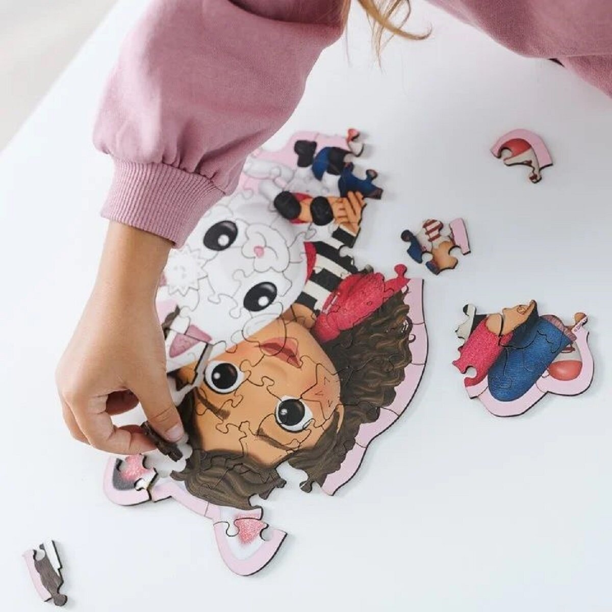 La mano de un niño colocando una pieza de rompecabezas en un rompecabezas de Gabby's Dollhouse.