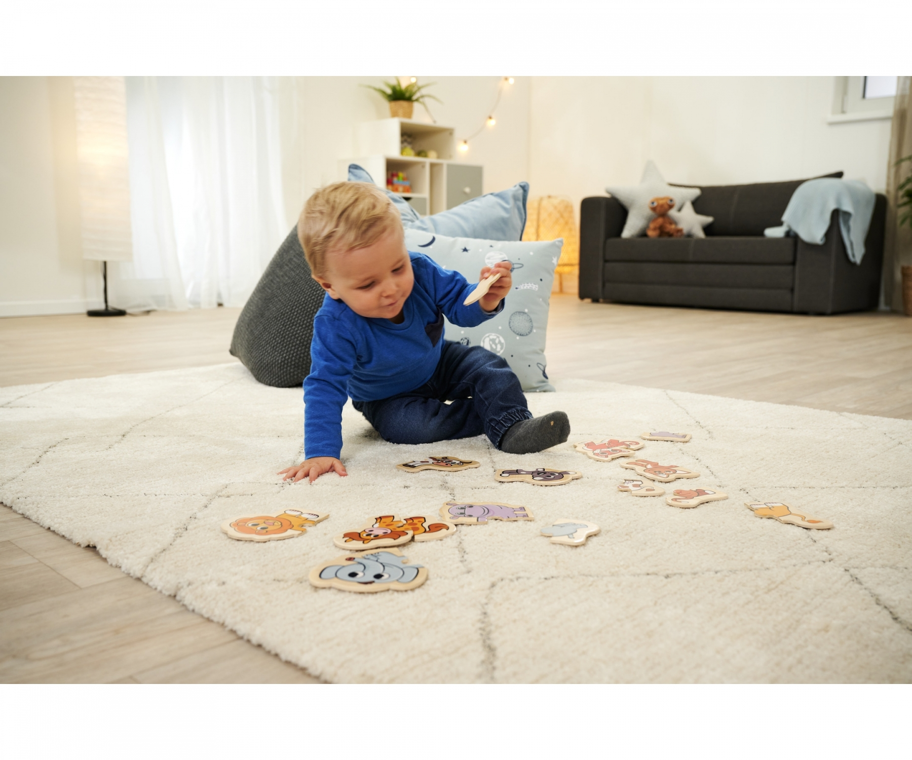 Ein Kleinkind spielt mit Holzpuzzles auf einem flauschigen weißen Teppich.