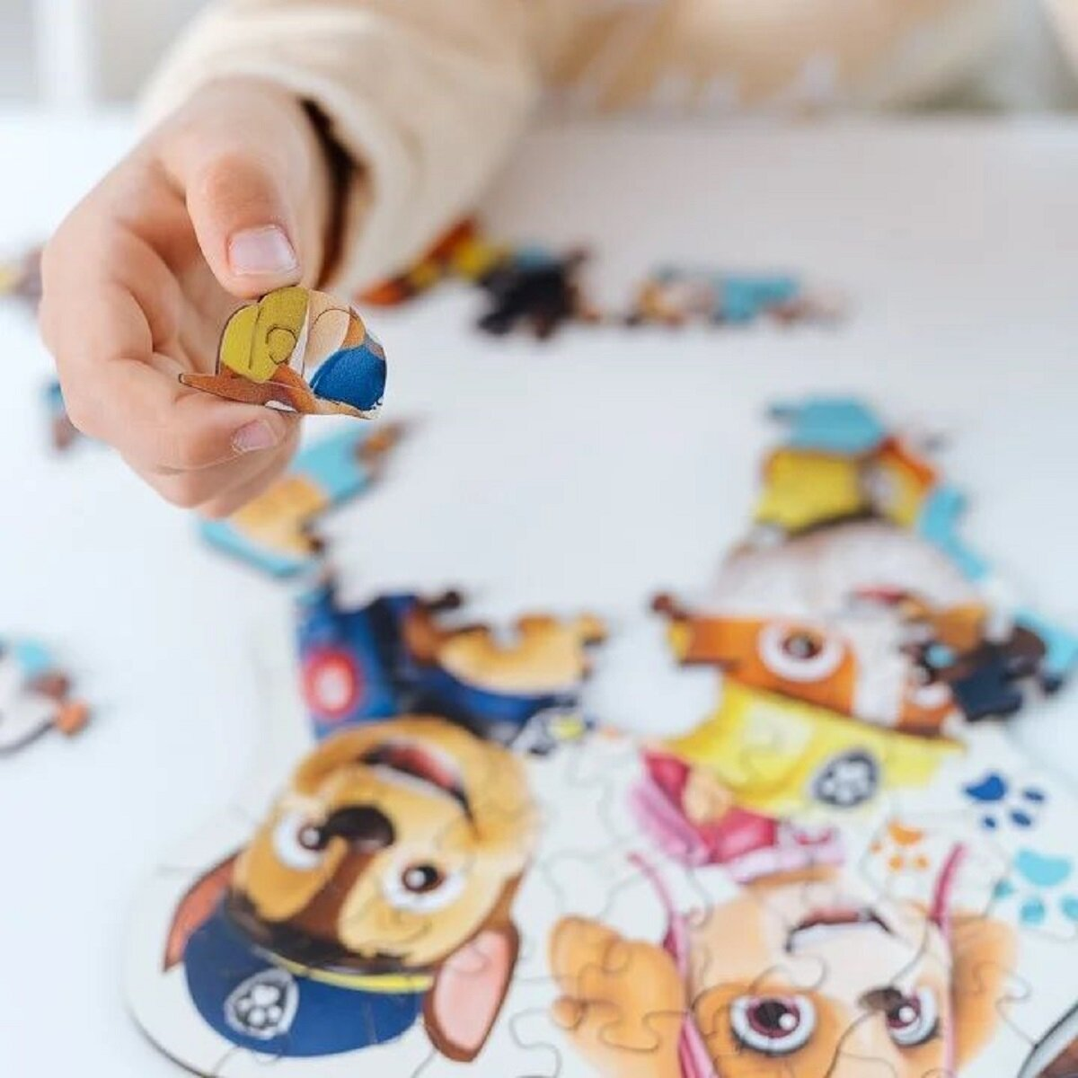 La mano de un niño sosteniendo una pieza de rompecabezas con la cara de un perro de dibujos animados.