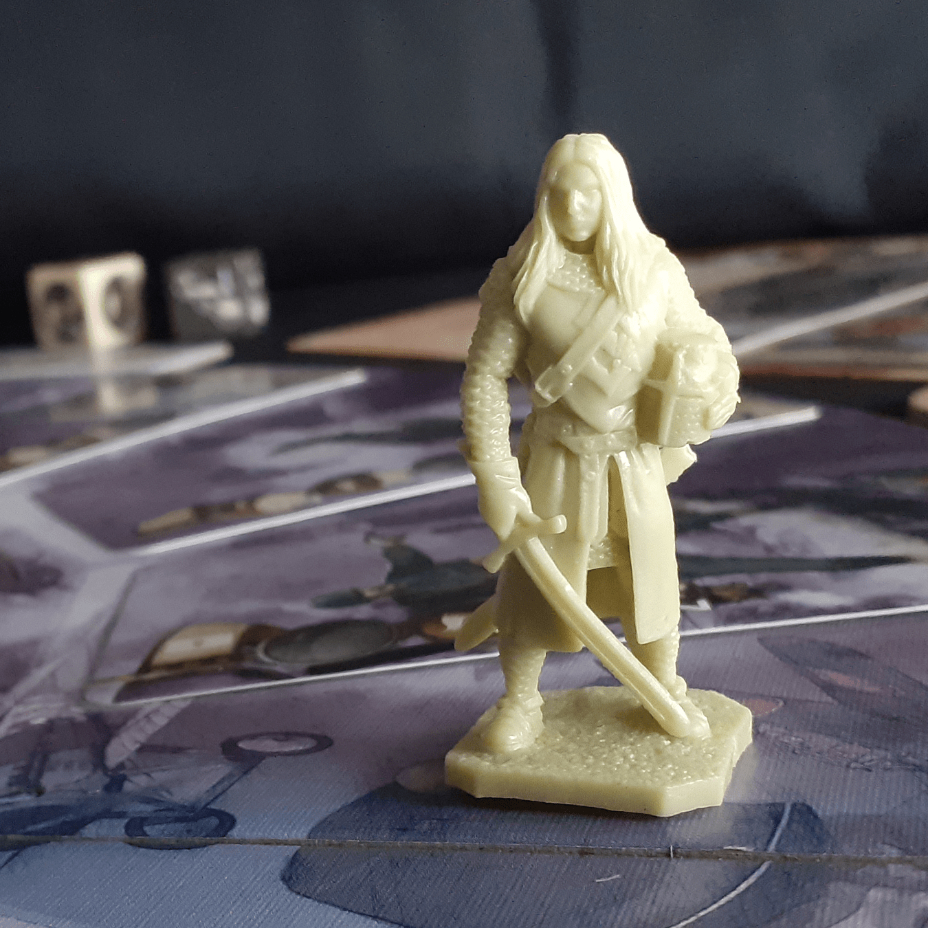 Eine hellplastische Figur eines Kriegers mit Schwert und Schild steht auf einem Spielbrett.