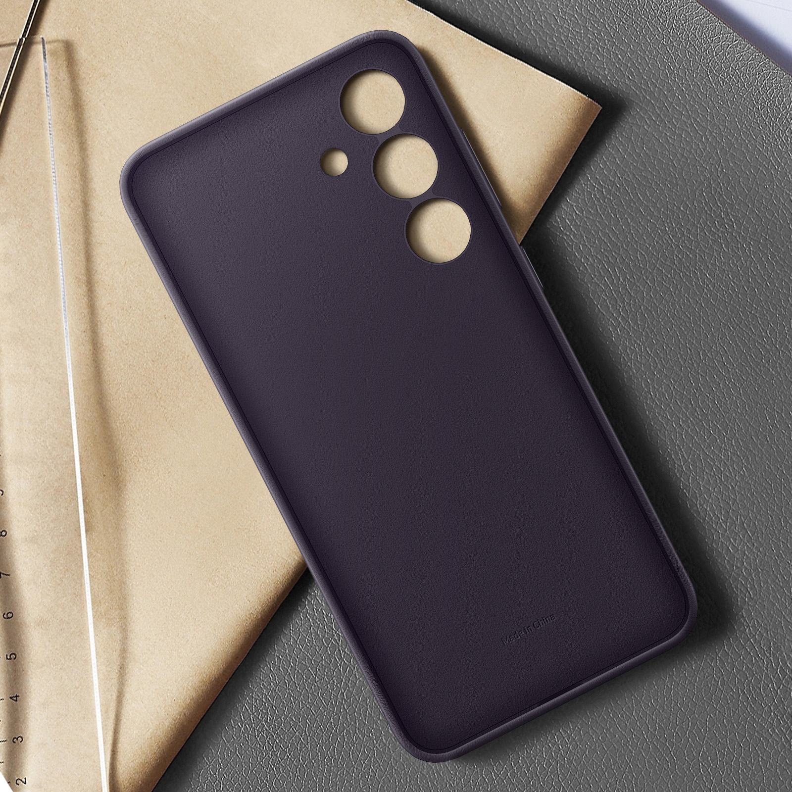Violette Handyhülle mit drei Kameralöchern auf einem Tisch mit Lineal.
