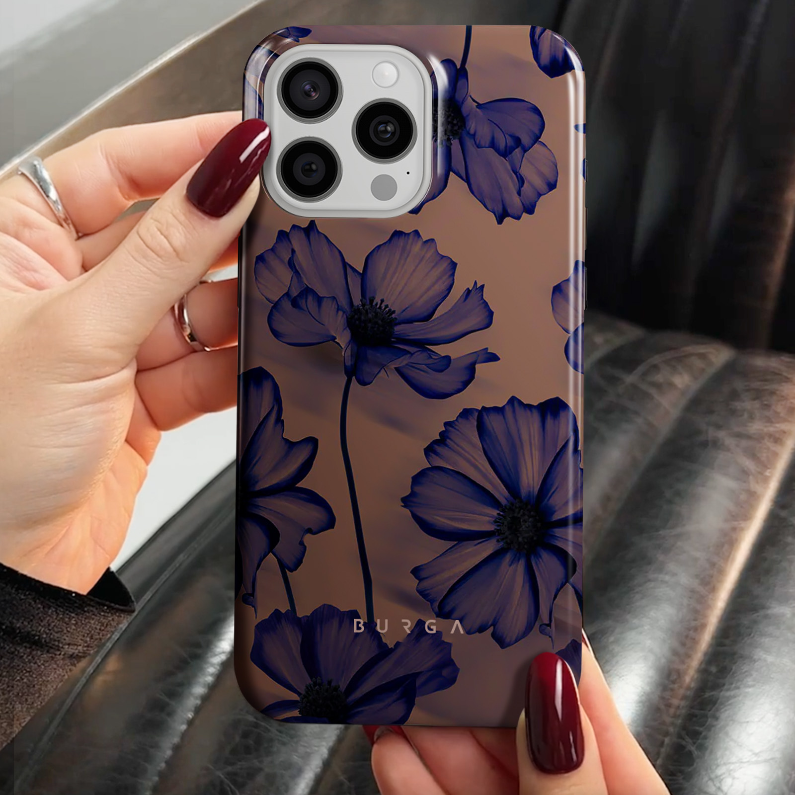 Main tenant une coque de téléphone avec un motif de fleurs bleues.