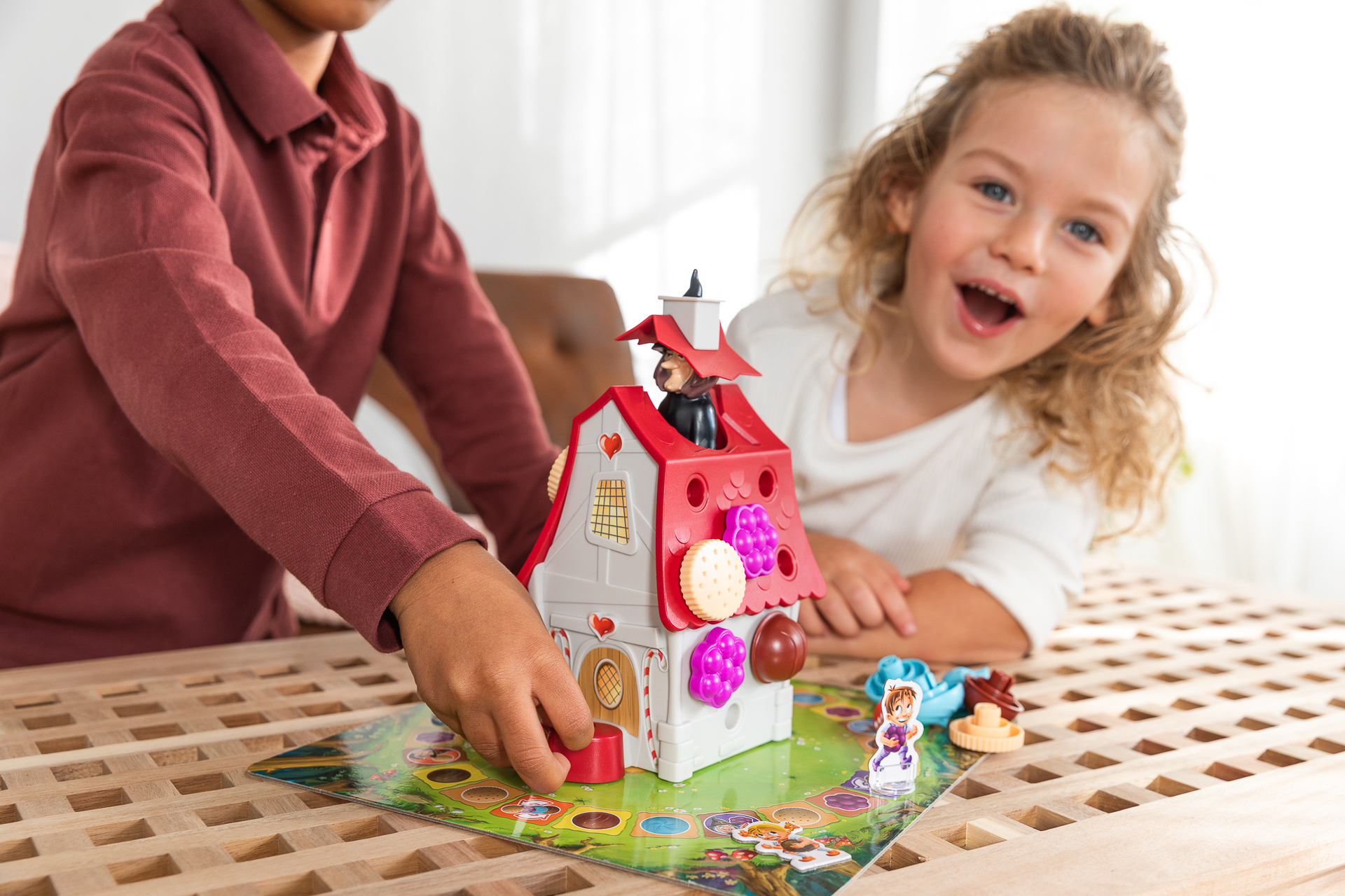 Twee kinderen spelen een speelgoedhuisspel. Een kind plaatst een stuk op het spelbord.