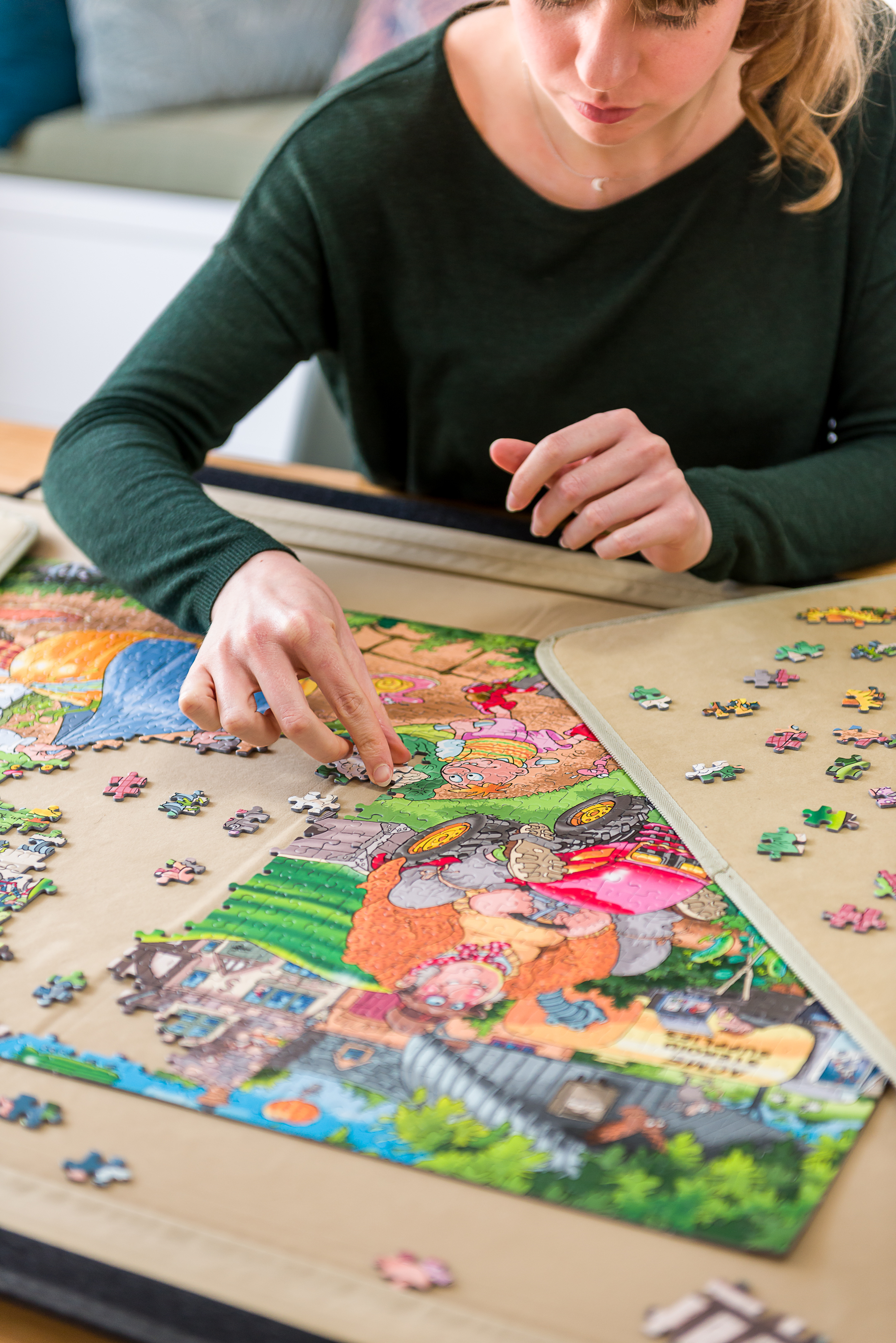 Woman assembling a jigsaw puzzle with a colorful village scene.