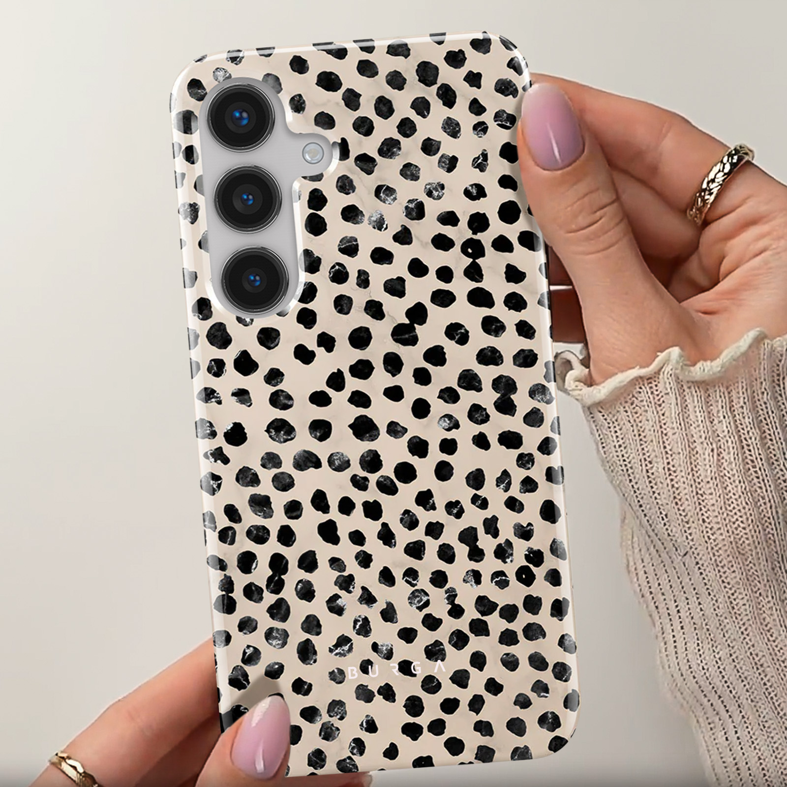 Una custodia per telefono con un motivo a pois dalmata in bianco e nero. La custodia è tenuta da una persona.