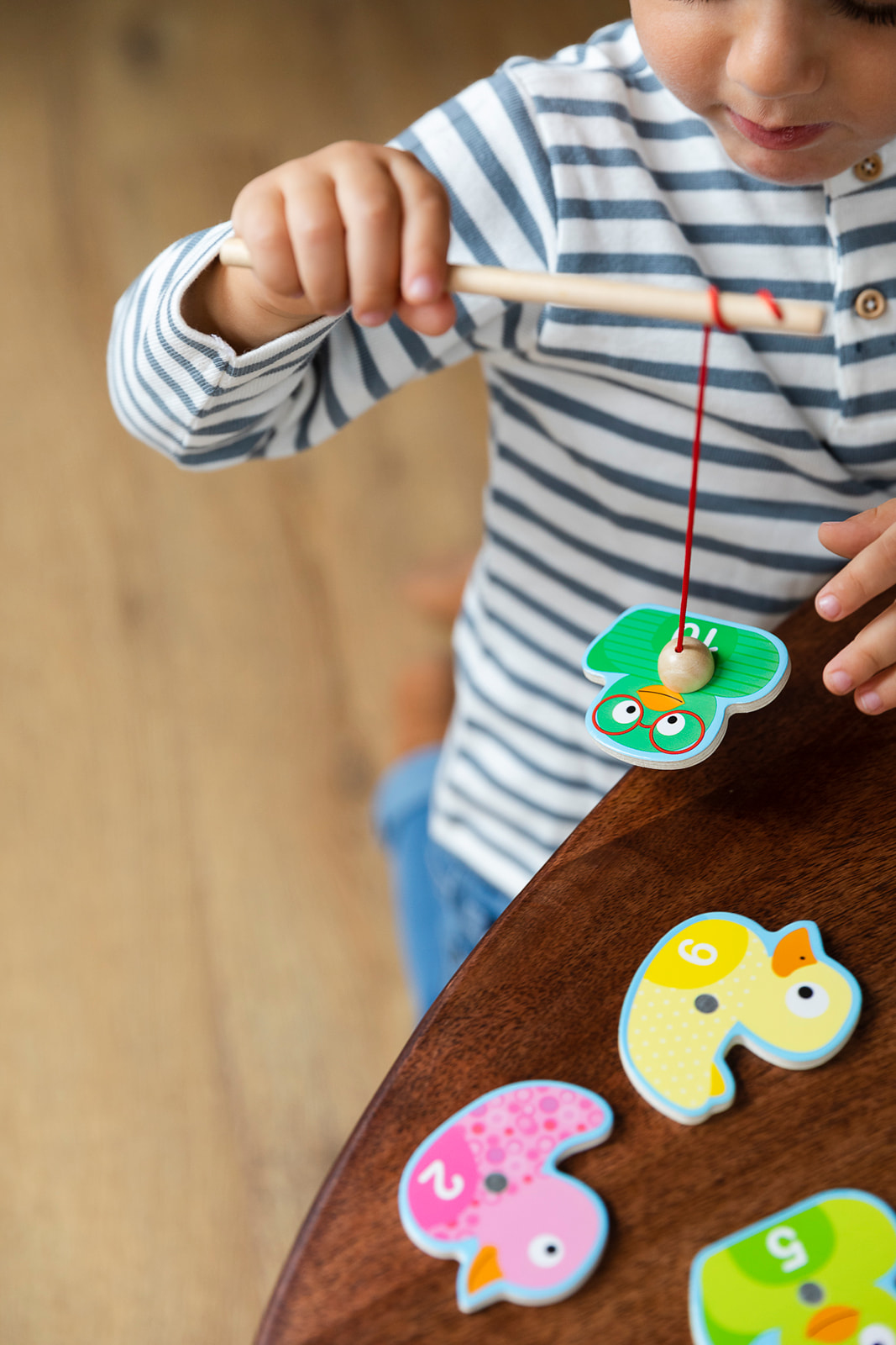 Dziecko bawi się wędkarstwem. Liczby na rybach, drewniana wędka.