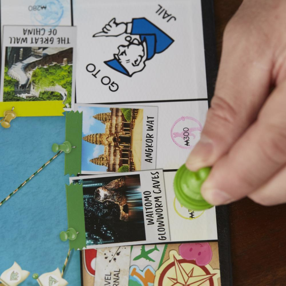 Monopoly-Brett mit Karten. Ein grünes Spielteil wird auf eine Karte eines Ortes gelegt.