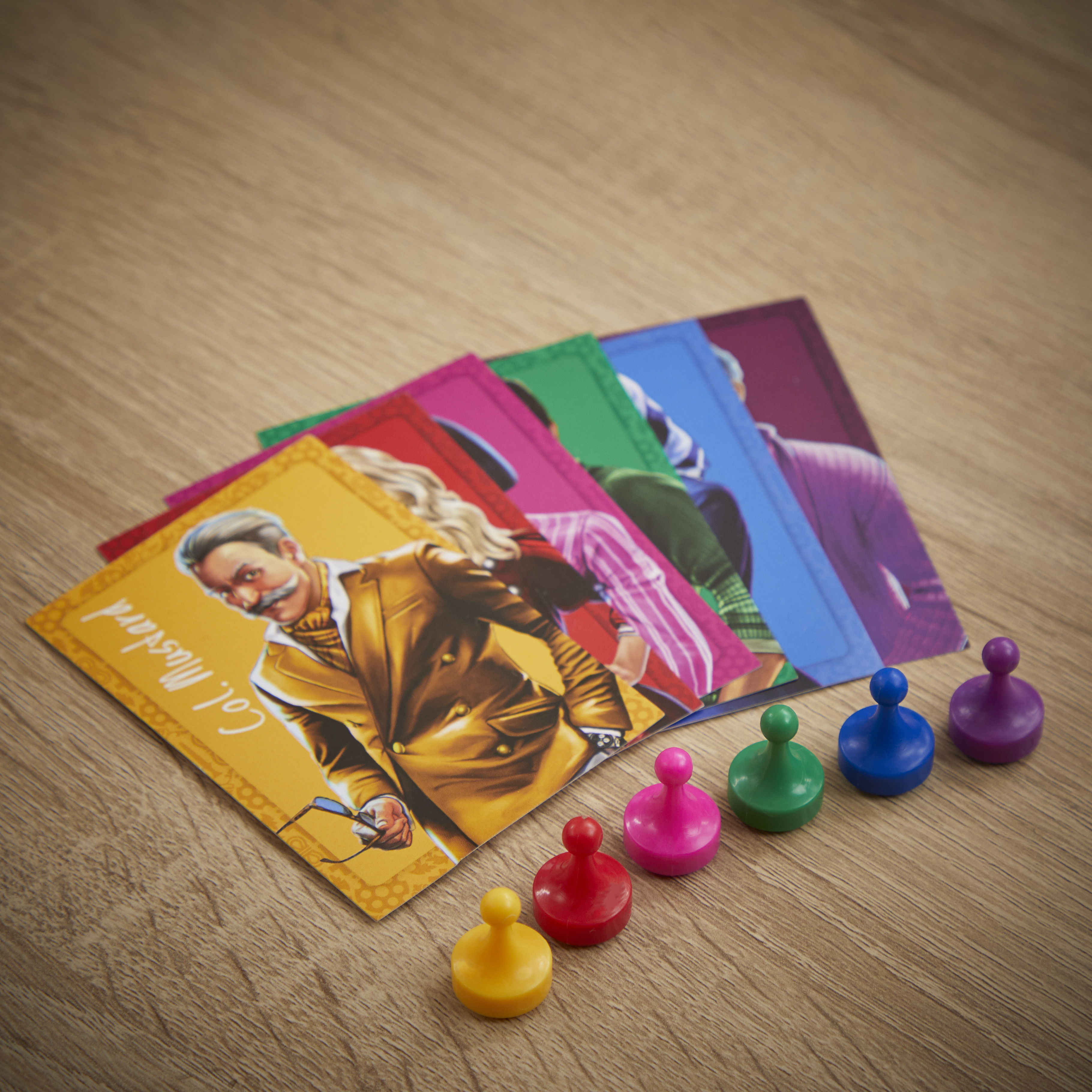 Cluedo-Spielkarten und Spielsteine auf einem Holztisch. Die Karte 'Col Mustard' ist sichtbar.