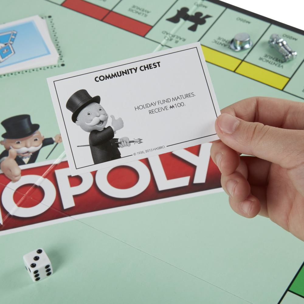 Hand hält eine Gemeinschaftskarten über einem Monopoly-Brett. Karte sagt: 'Urlaubsfonds fällig. Erhalte 100 $'.
