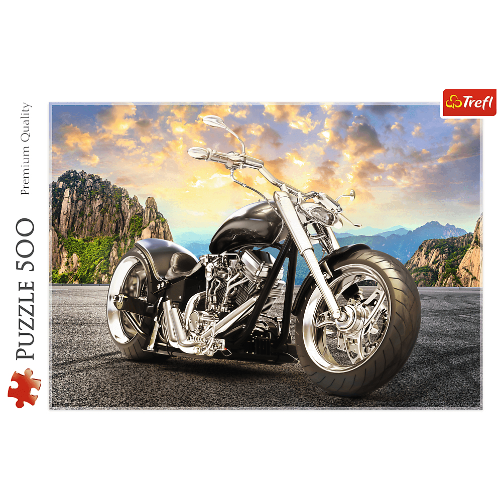 Motocicletta nera su una strada, montagne sullo sfondo, cielo al tramonto.