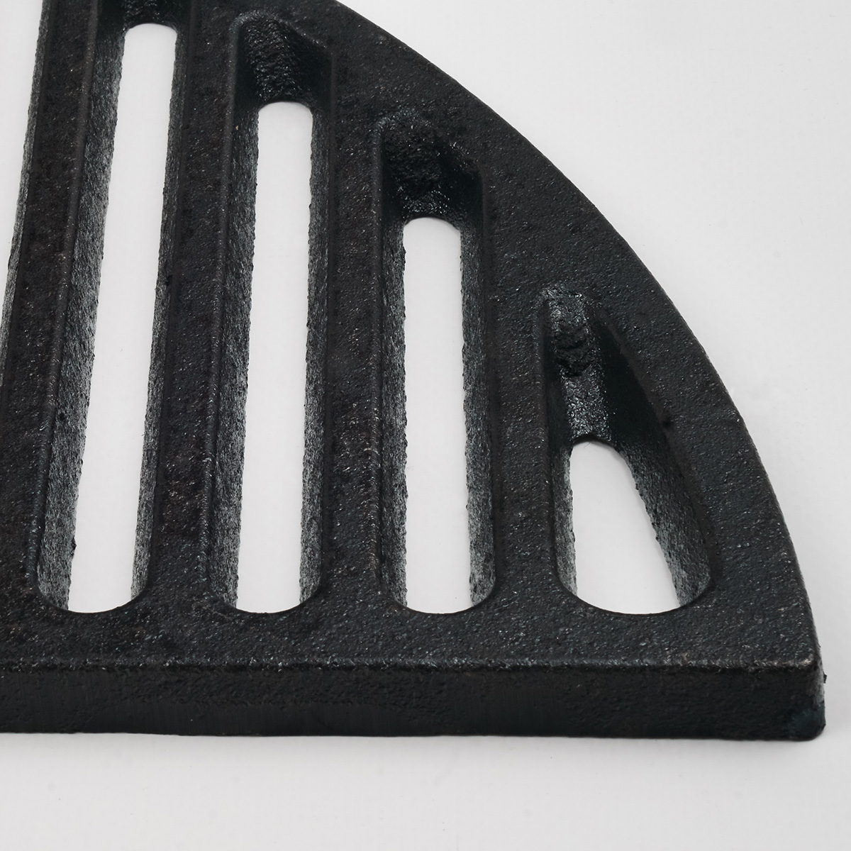 Close-up of a black cast iron grate with vertical slots and rounded corners.