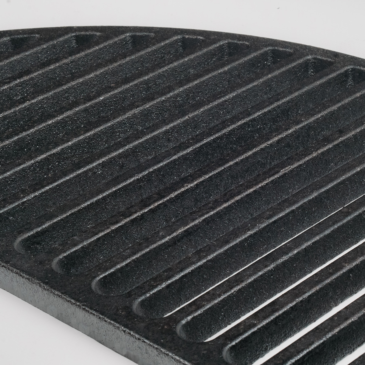 Close-up of a black, ridged grill grate. The ridges are parallel and curved.