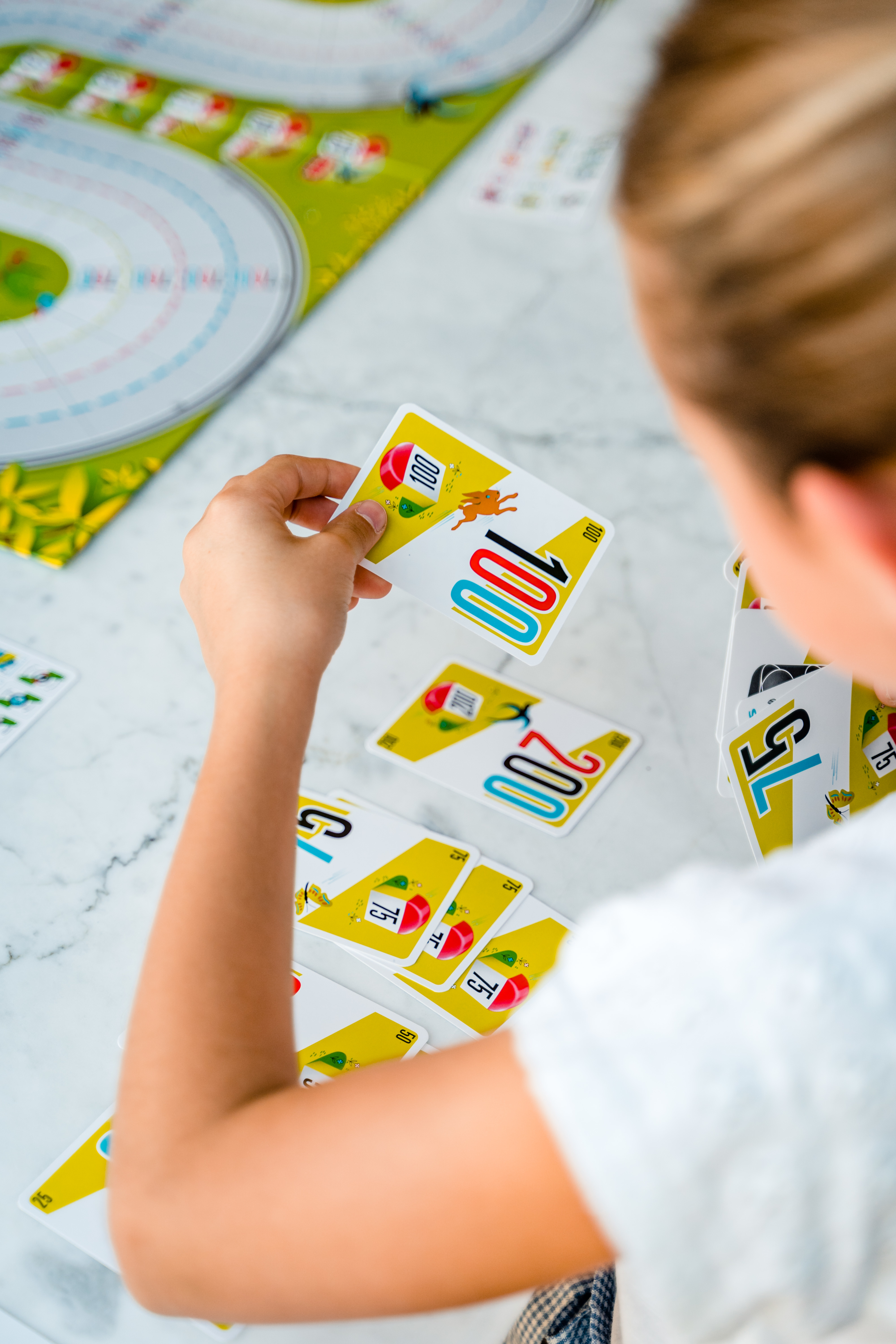 A person is holding and looking at playing cards. The cards have numbers and colors on them.