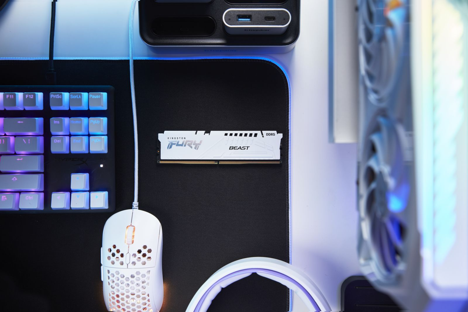 Elementy komputera na biurku: klawiatura, mysz, kość RAM i część komputera.