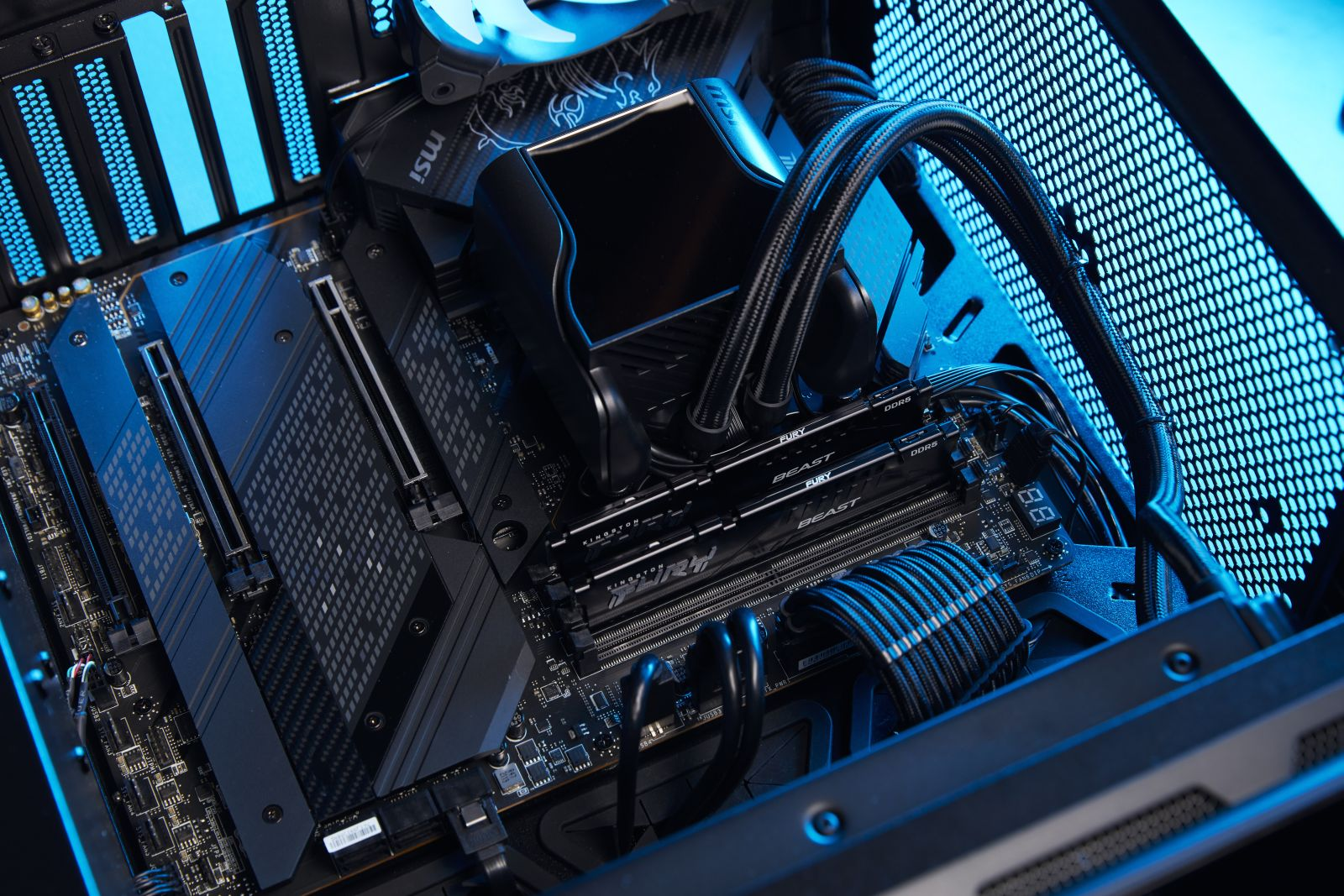 Podzespoły komputera w obudowie: płyta główna, chłodzenie, pamięć RAM i różne kable.