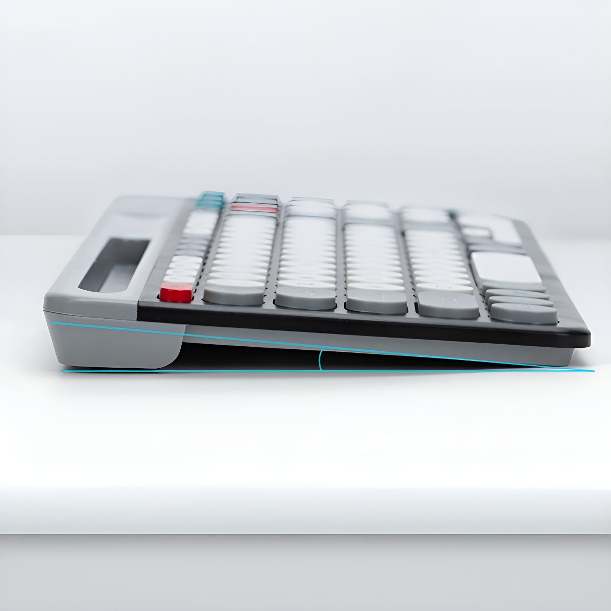 Eine geneigte graue Tastatur auf einer weißen Oberfläche. Rote und weiße Tasten sind sichtbar mit einer blauen Linie, die den Neigungswinkel zeigt.