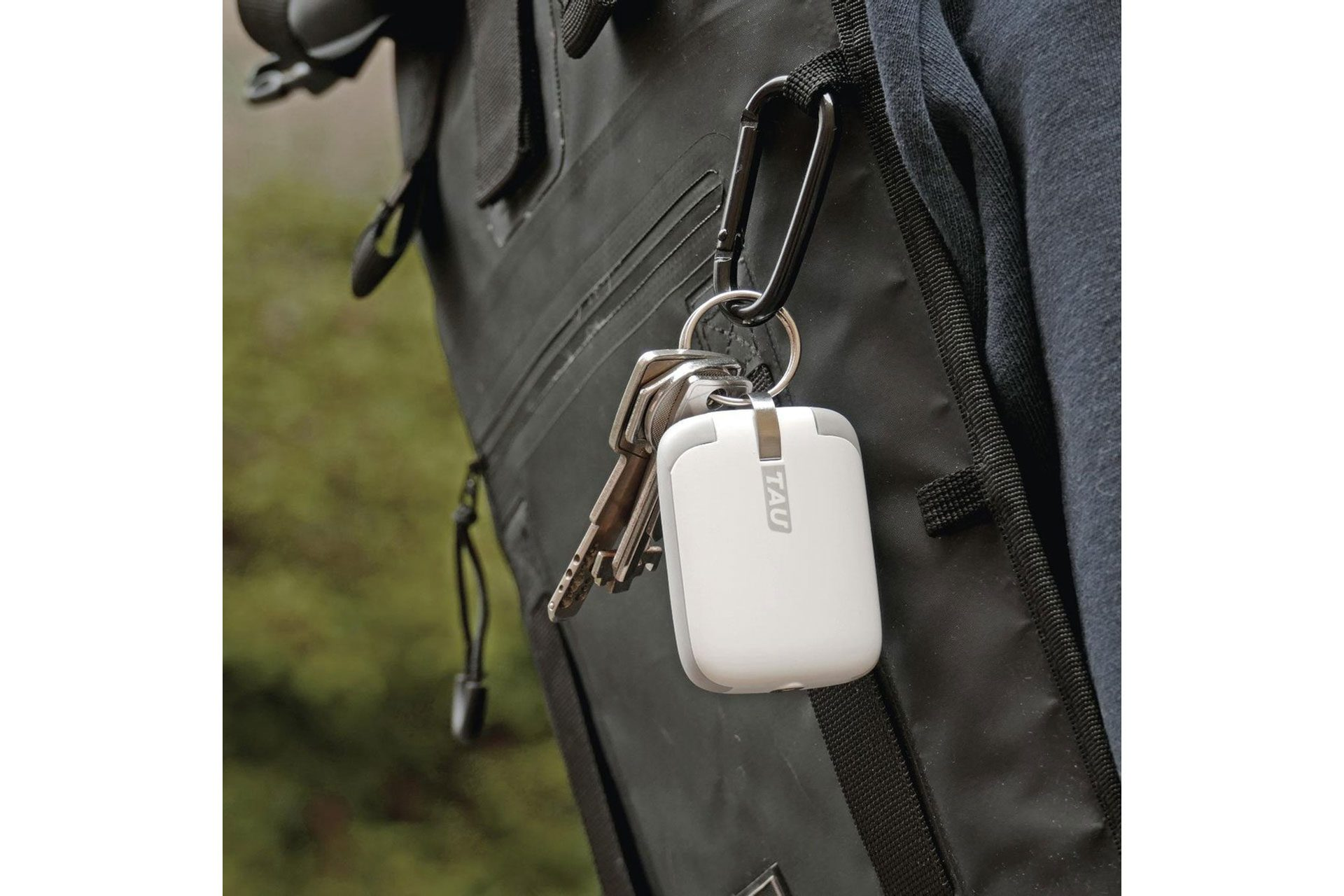 Sleutels met een witte tracker bevestigd aan een zwarte tas. Een zilveren karabijnhaak wordt gebruikt.