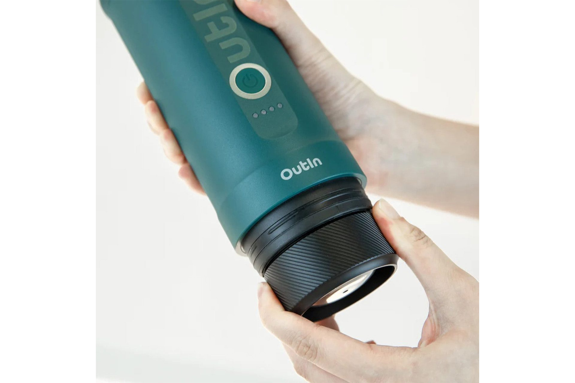 Ręce skręcają czarną podstawę butelki Outin w kolorze morskim. Białe tło.