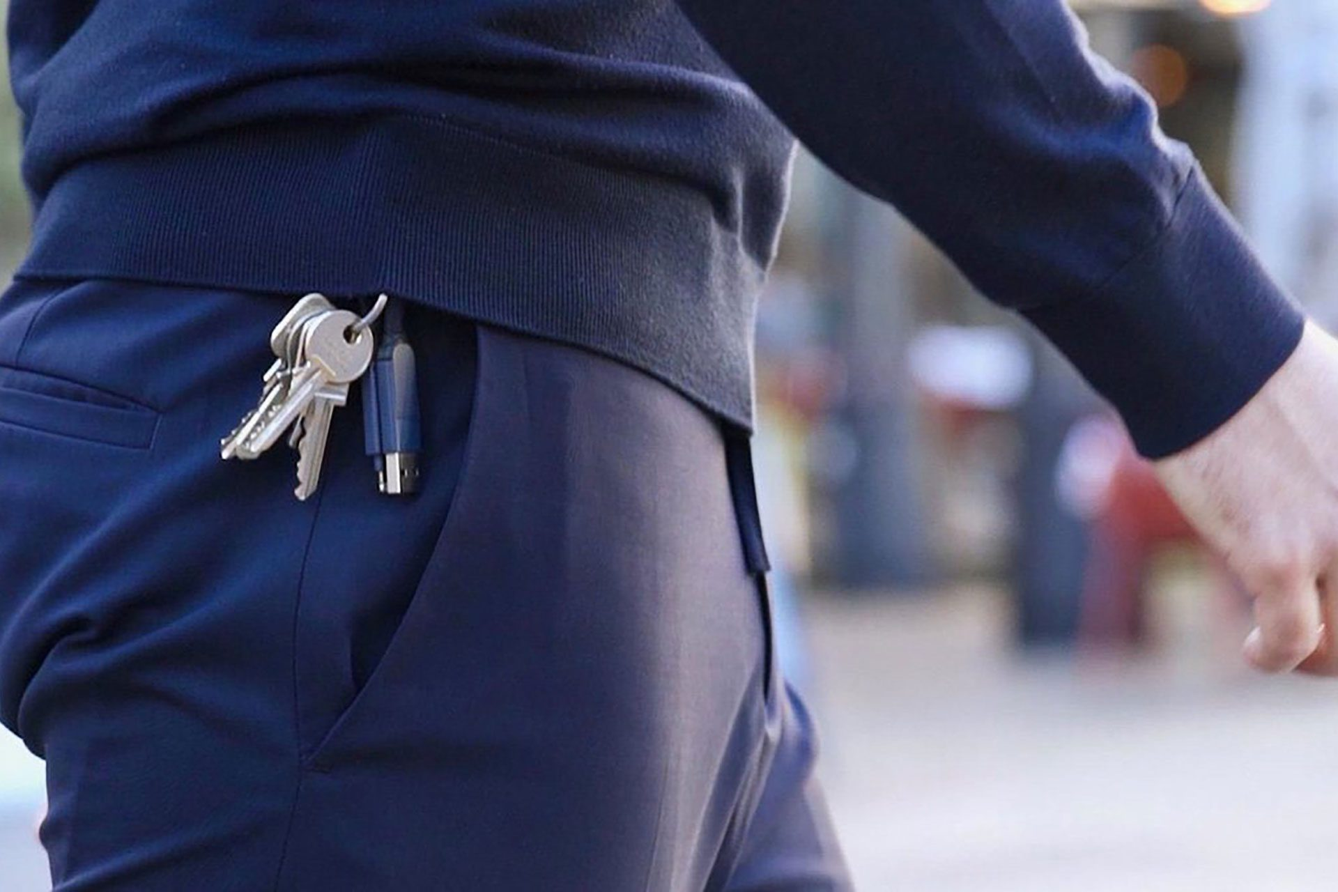 Een persoon met sleutels en een pen in de zak, lopend. De broek is marineblauw.