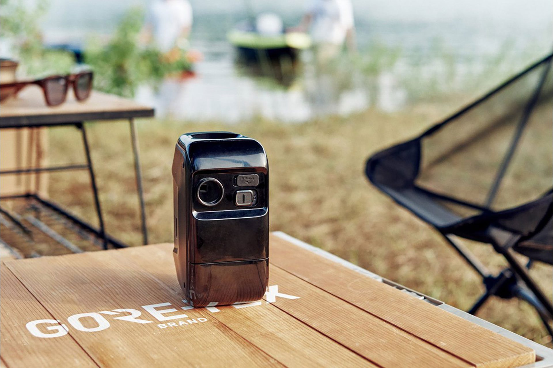 Tragbare Stromstation auf Holztisch, See im Hintergrund.