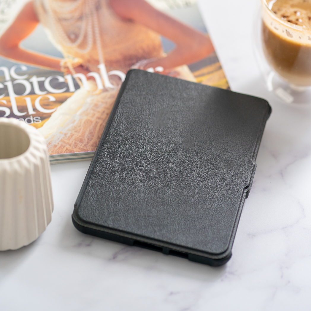 Un étui de tablette noir fermé est montré sur une surface en marbre à côté d'un magazine.