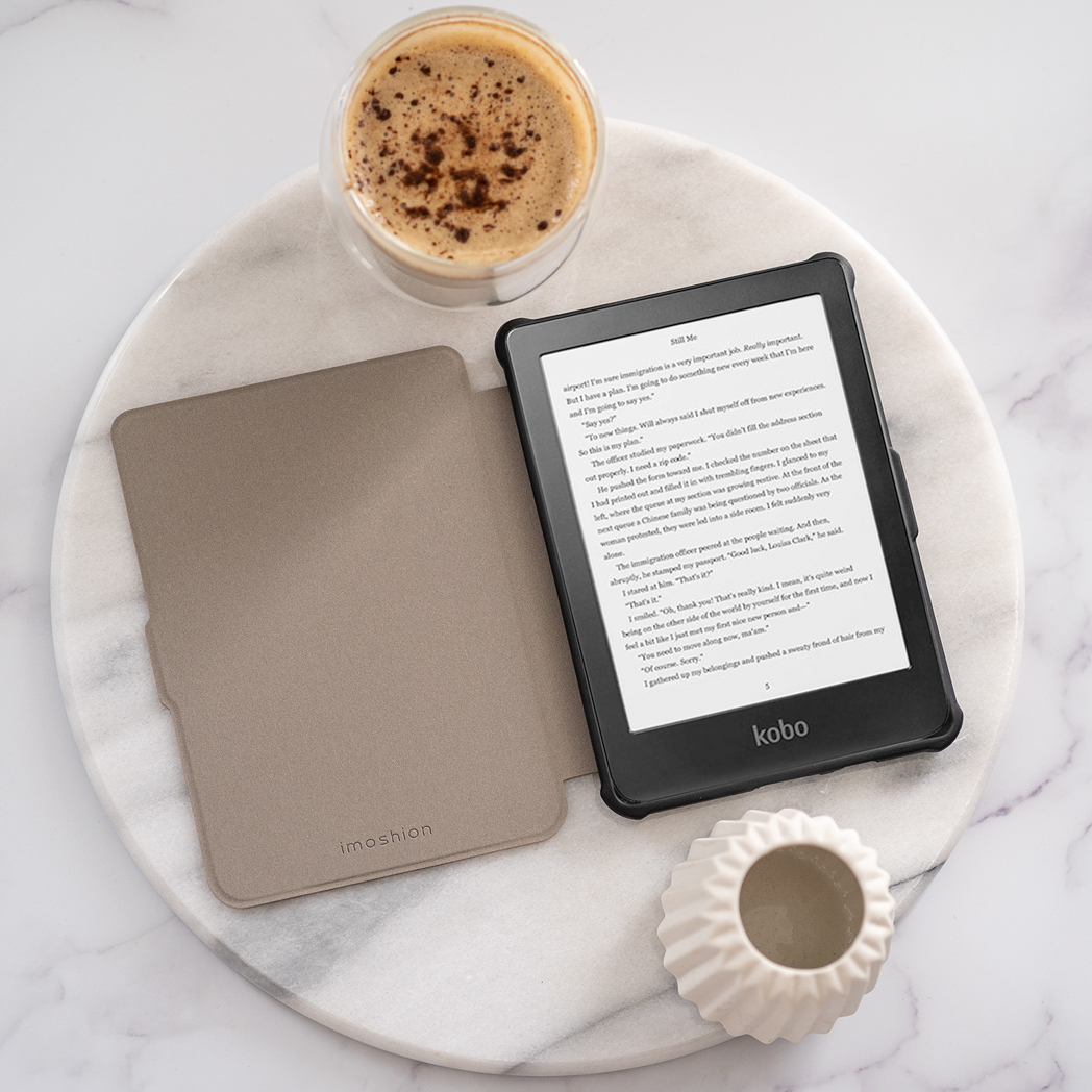 Open boek en kaft met een koffiekopje. Witte tafel, zwarte tablet met tekst en een witte vaas.