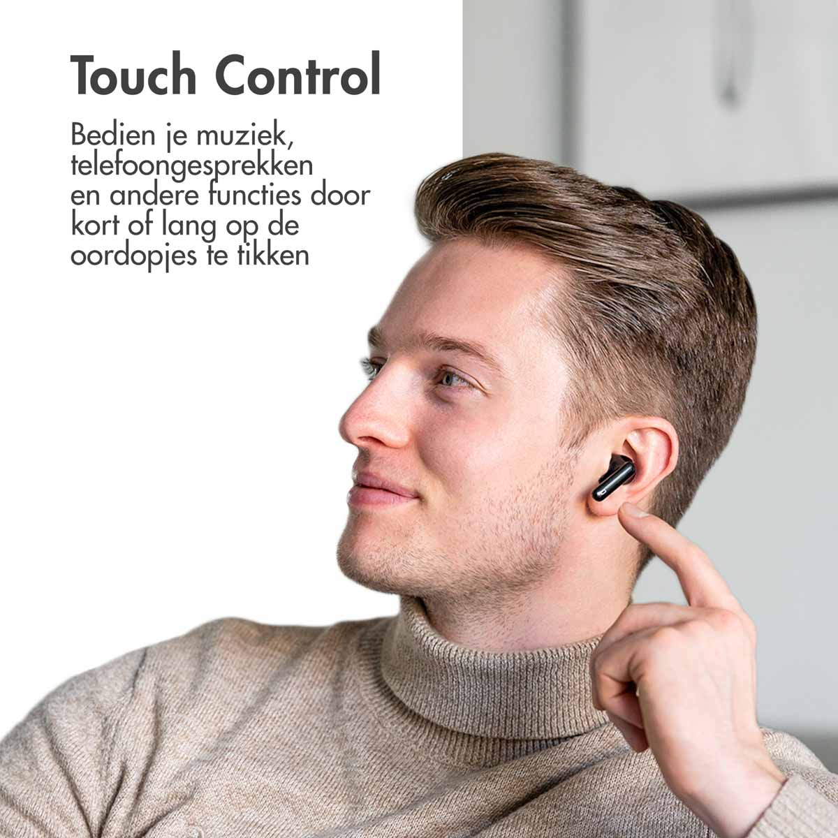 A man wearing a turtleneck smiles while wearing black earbuds.