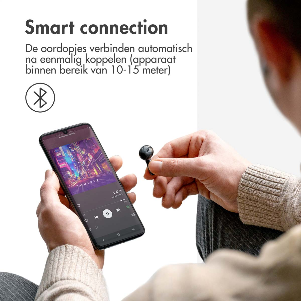 Person holding smartphone and earbud with Bluetooth connection.