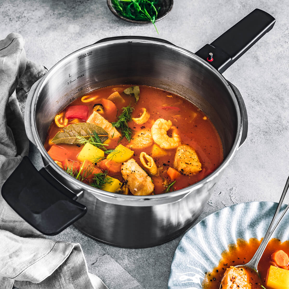 Una pentola con zuppa, con ingredienti come gamberi, pesce e verdure.
