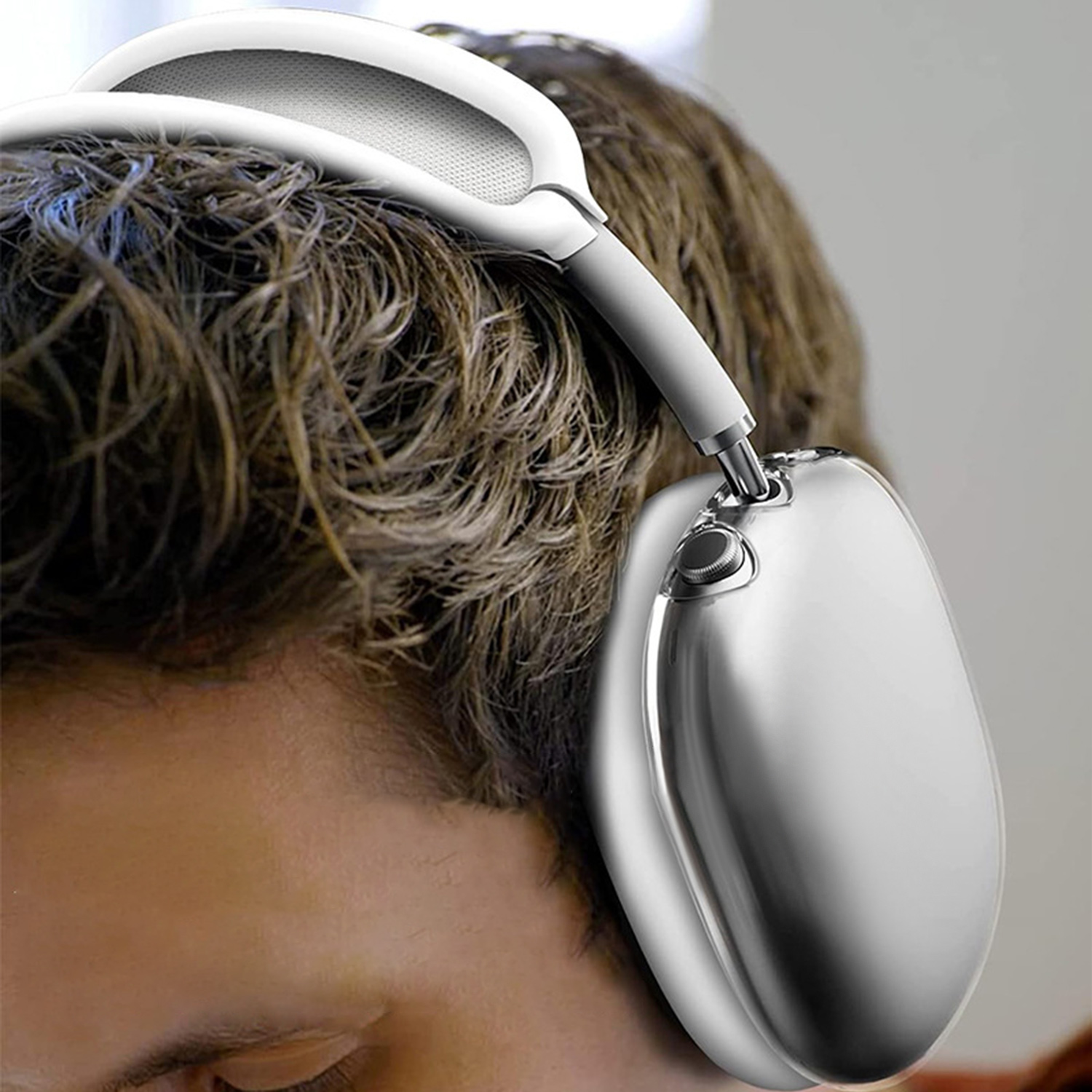 Ein Mann trägt silberne Kopfhörer. Die Kopfhörer sind weiß und grau mit Metallic-Finish.