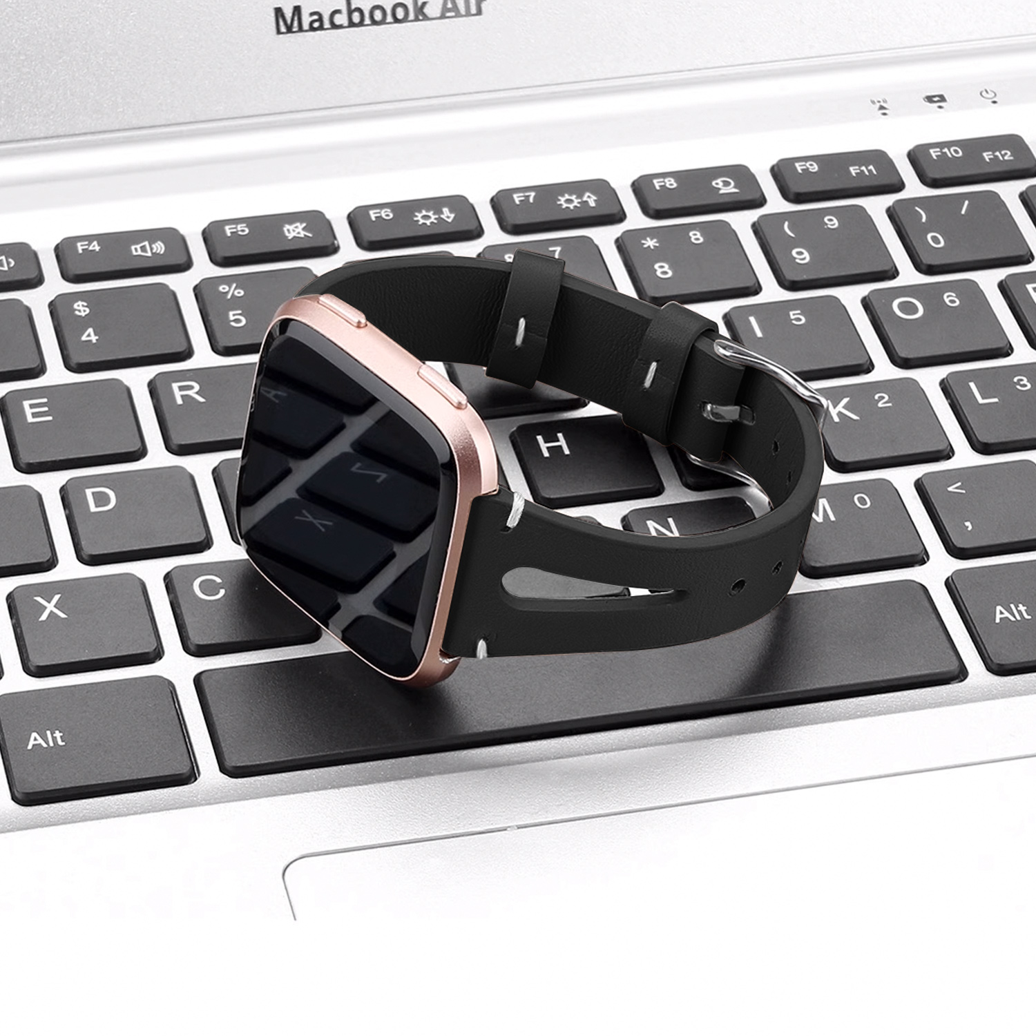 Smartwatch z czarnym paskiem na klawiaturze laptopa.