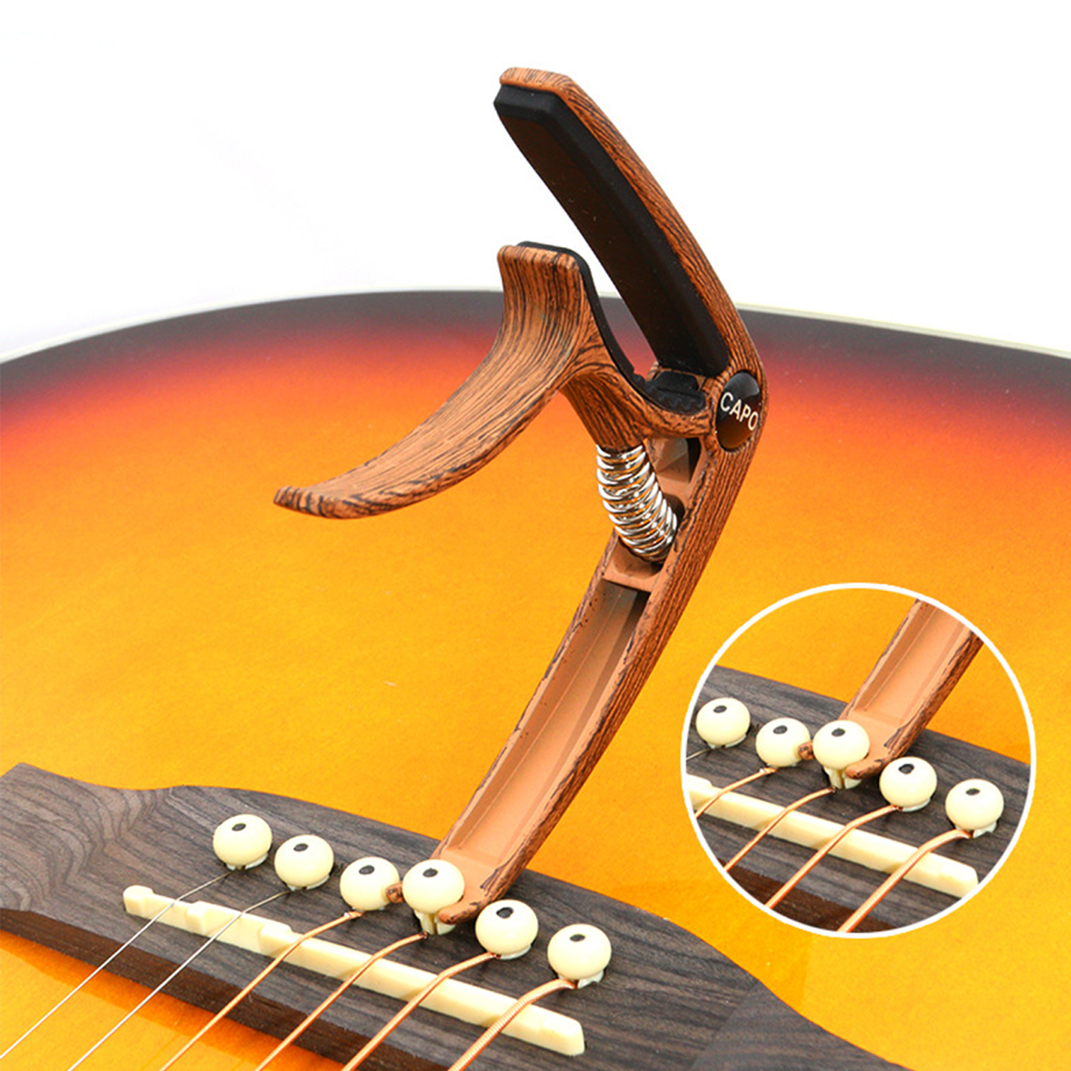 Ein brauner Gitarrenkapo. Es ist auf einer Gitarre. Die Gitarre ist braun, gelb und orange.