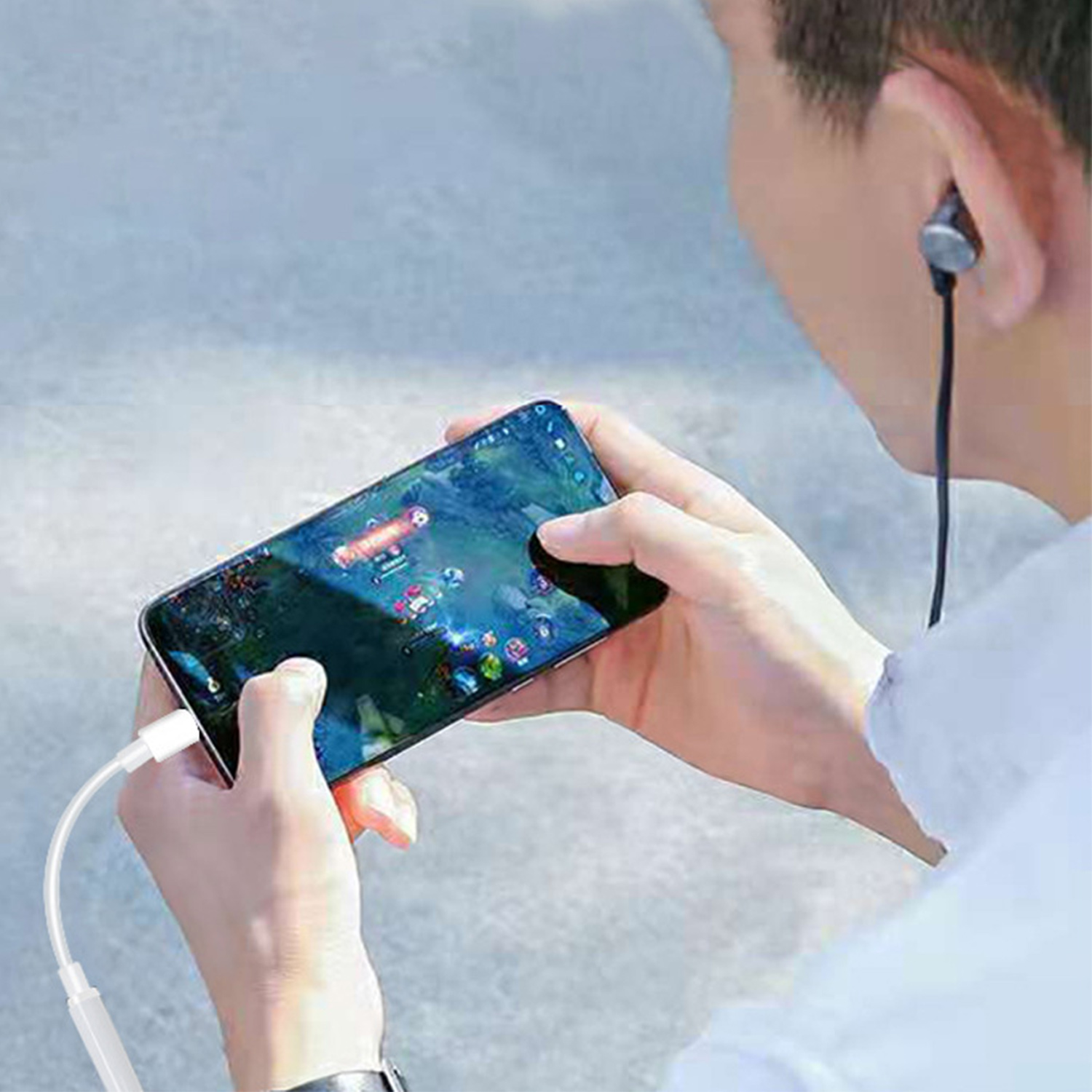 Una persona che gioca a un gioco su uno smartphone con le cuffie collegate. Il gioco mostra una grafica colorata.