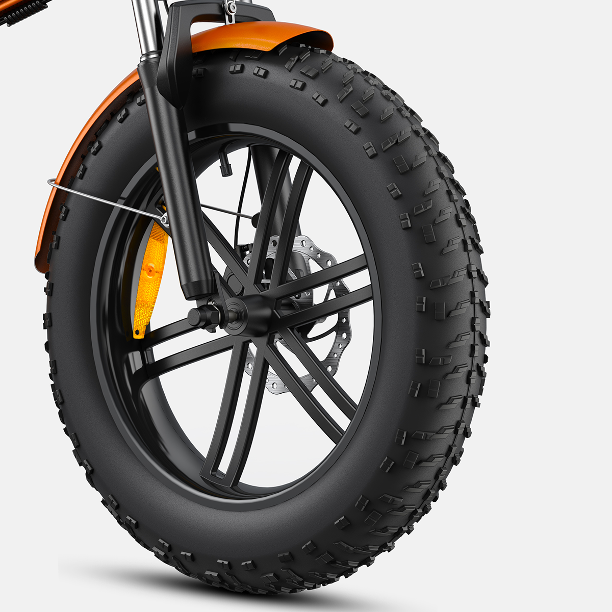 Przednie koło roweru z grubymi oponami, z pomarańczowym błotnikiem, hamulcem tarczowym i czarną oponą.